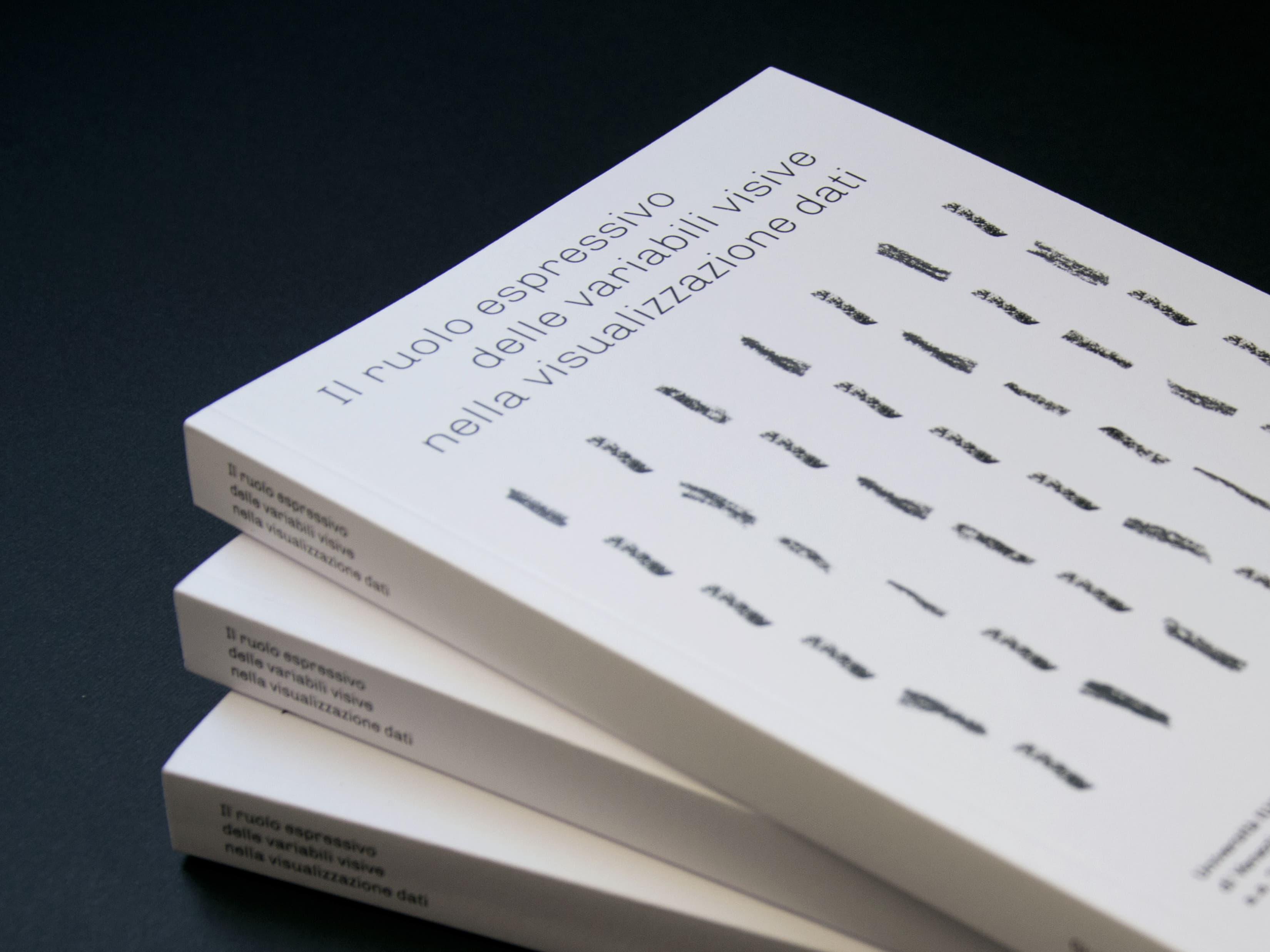 Stack of white books with black marks and Italian title text.