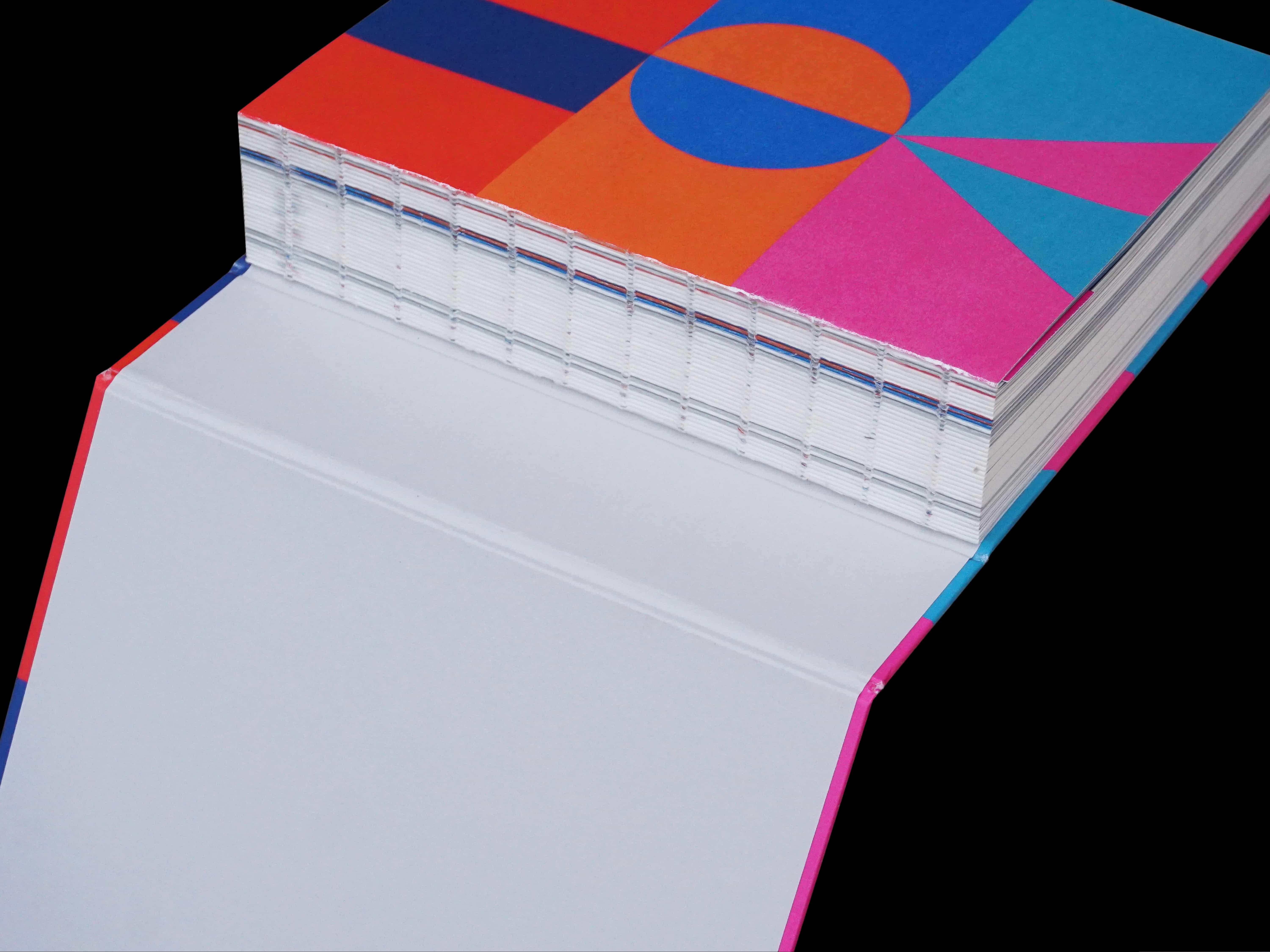 Close-up of the book's exposed sewn binding and geometric colour pattern, against black.