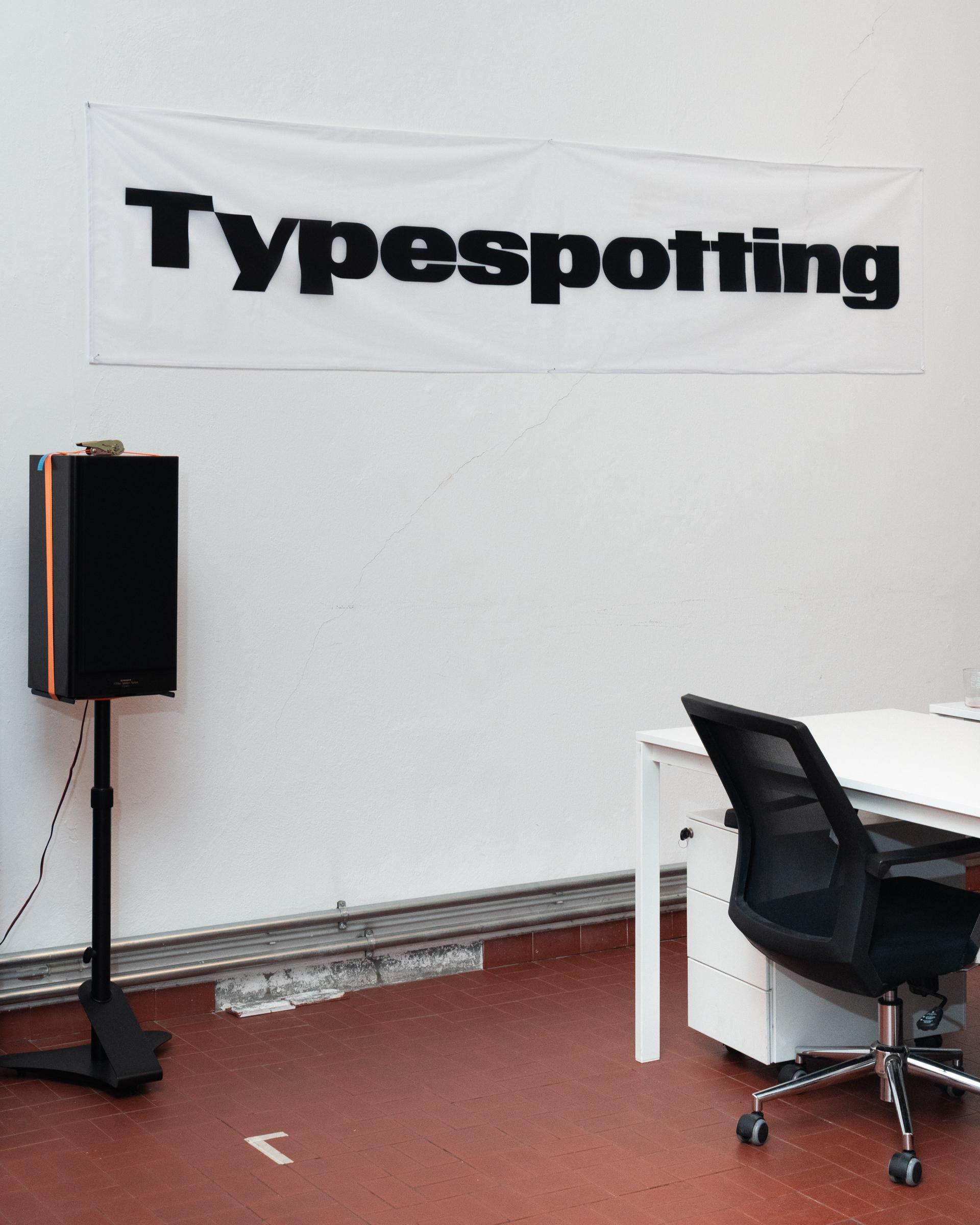 Typespotting banner above a desk and office chair in the Firm studio.
