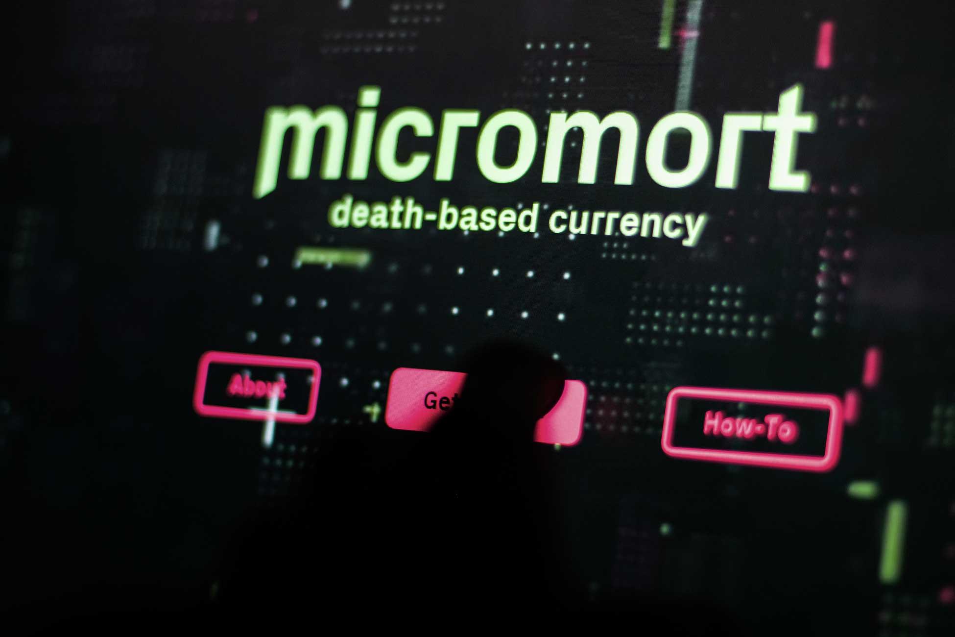 Laptop screen showing Micromort text and pink interface buttons.