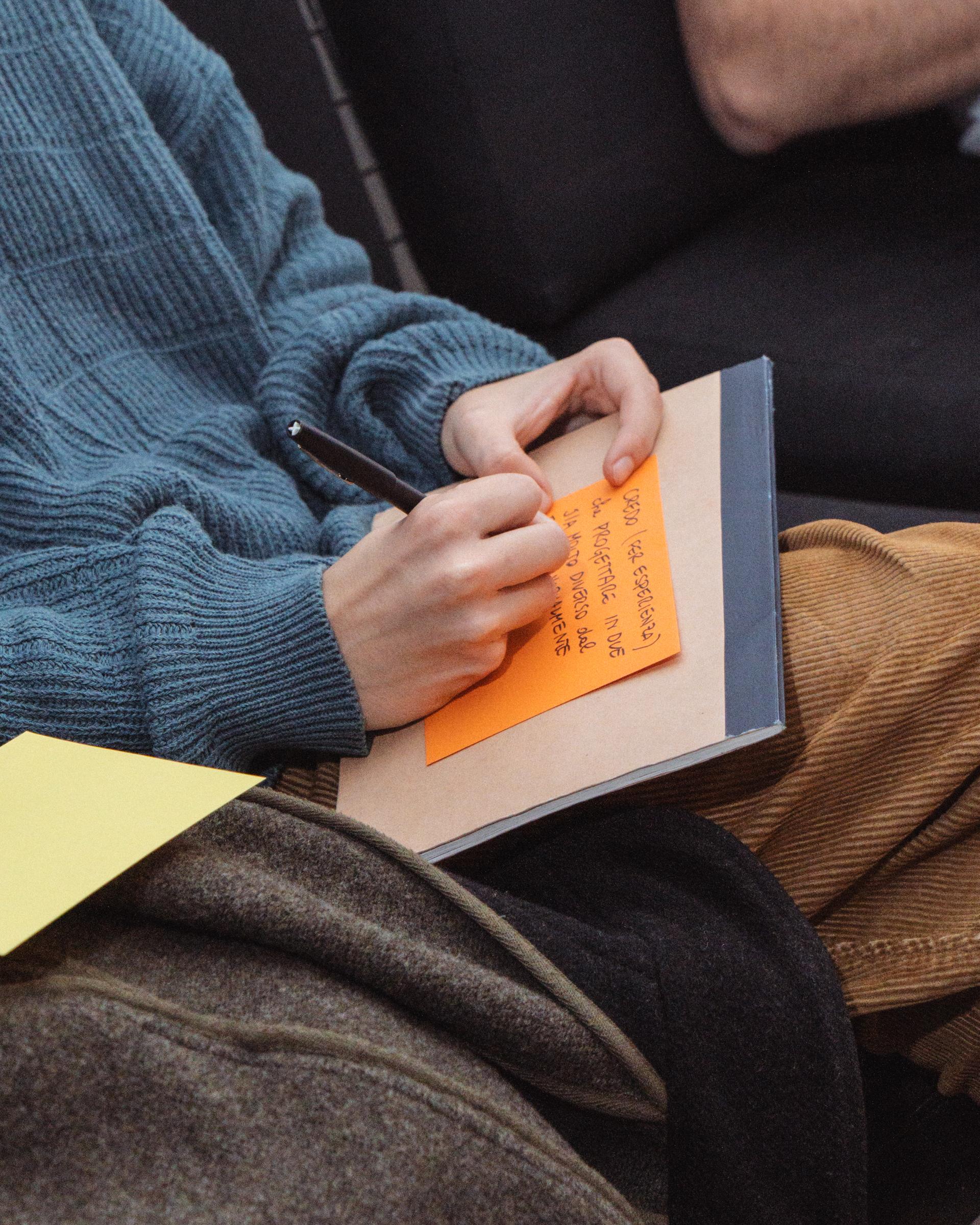 Participant writing on an orange note placed on a book.