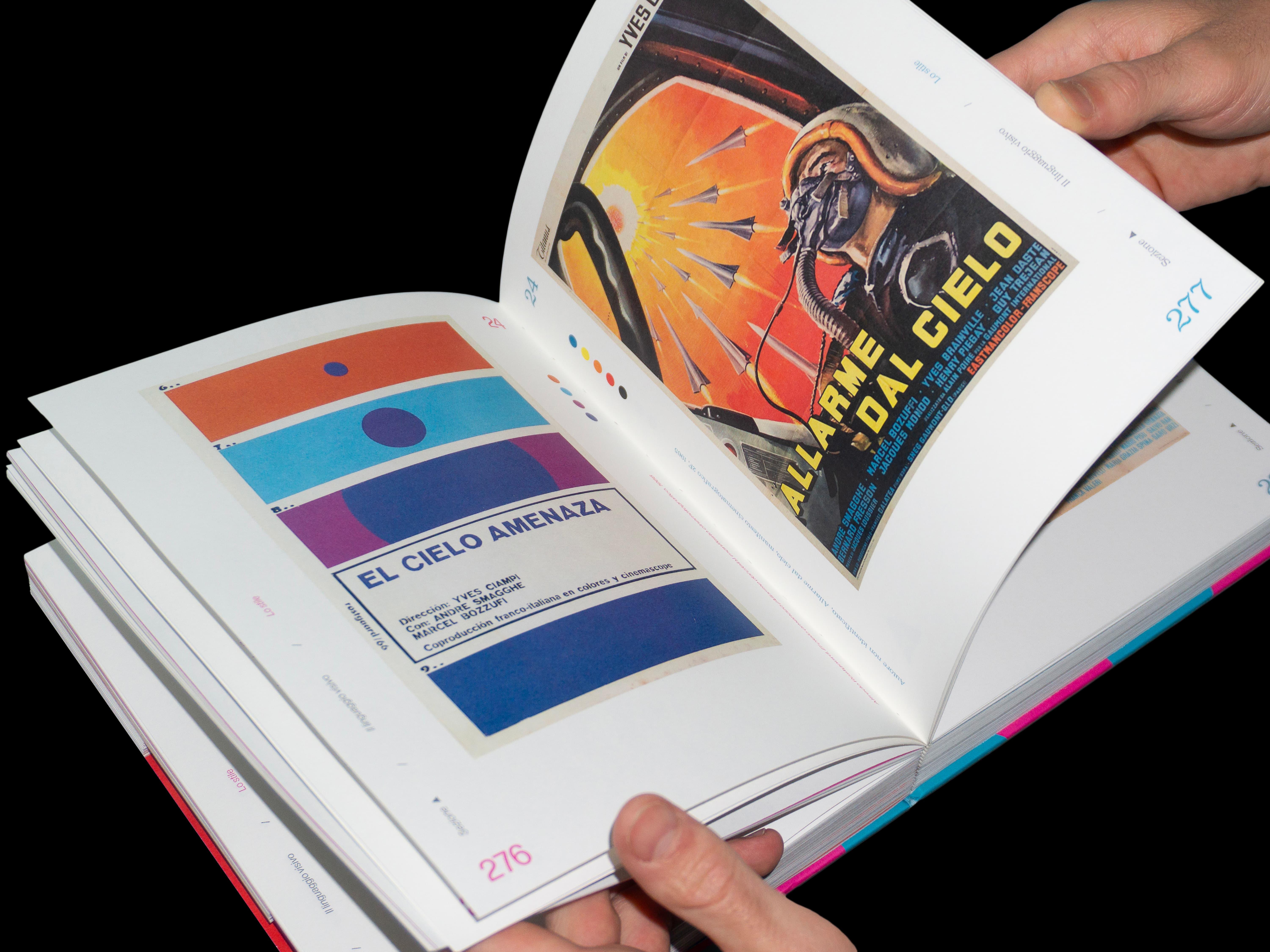 Hands turning the pages, showing a geometric Cuban poster for El cielo amenaza facing an Italian poster for Allarme dal cielo.