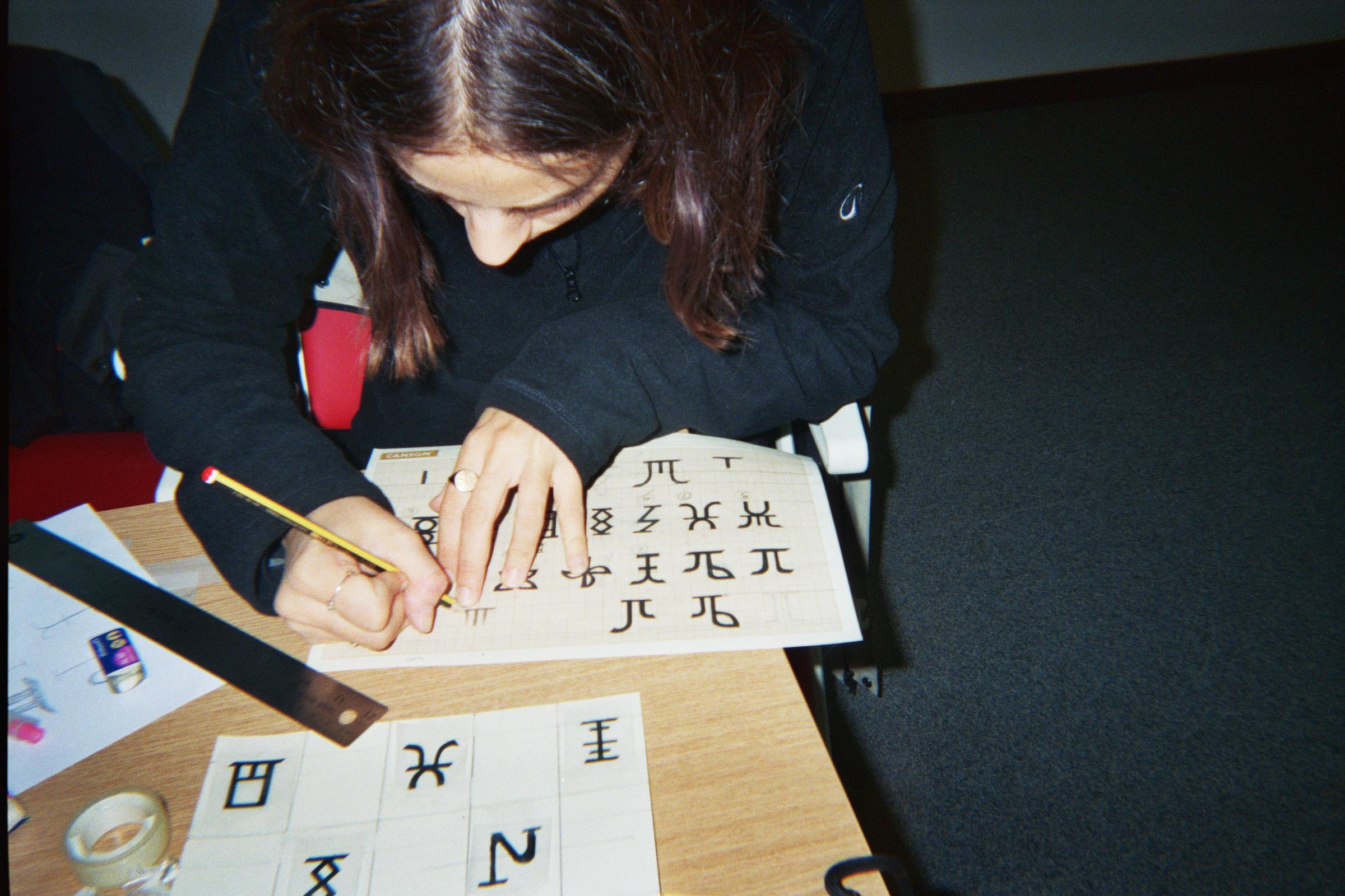 Participant drawing signs on a gridded sheet during the workshop.