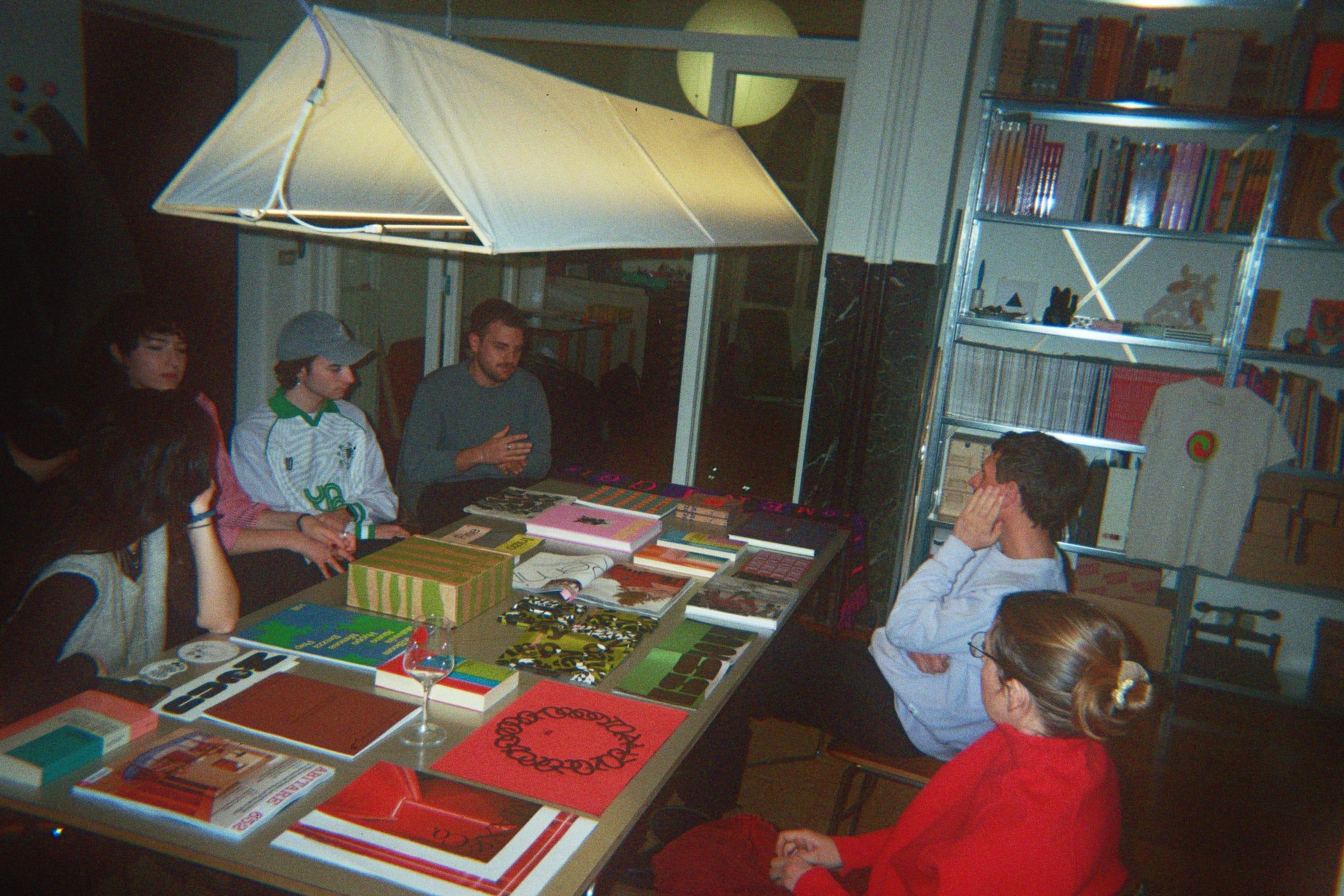 Attendees gathered around a table covered with books and printed work during the LaTigre visit.