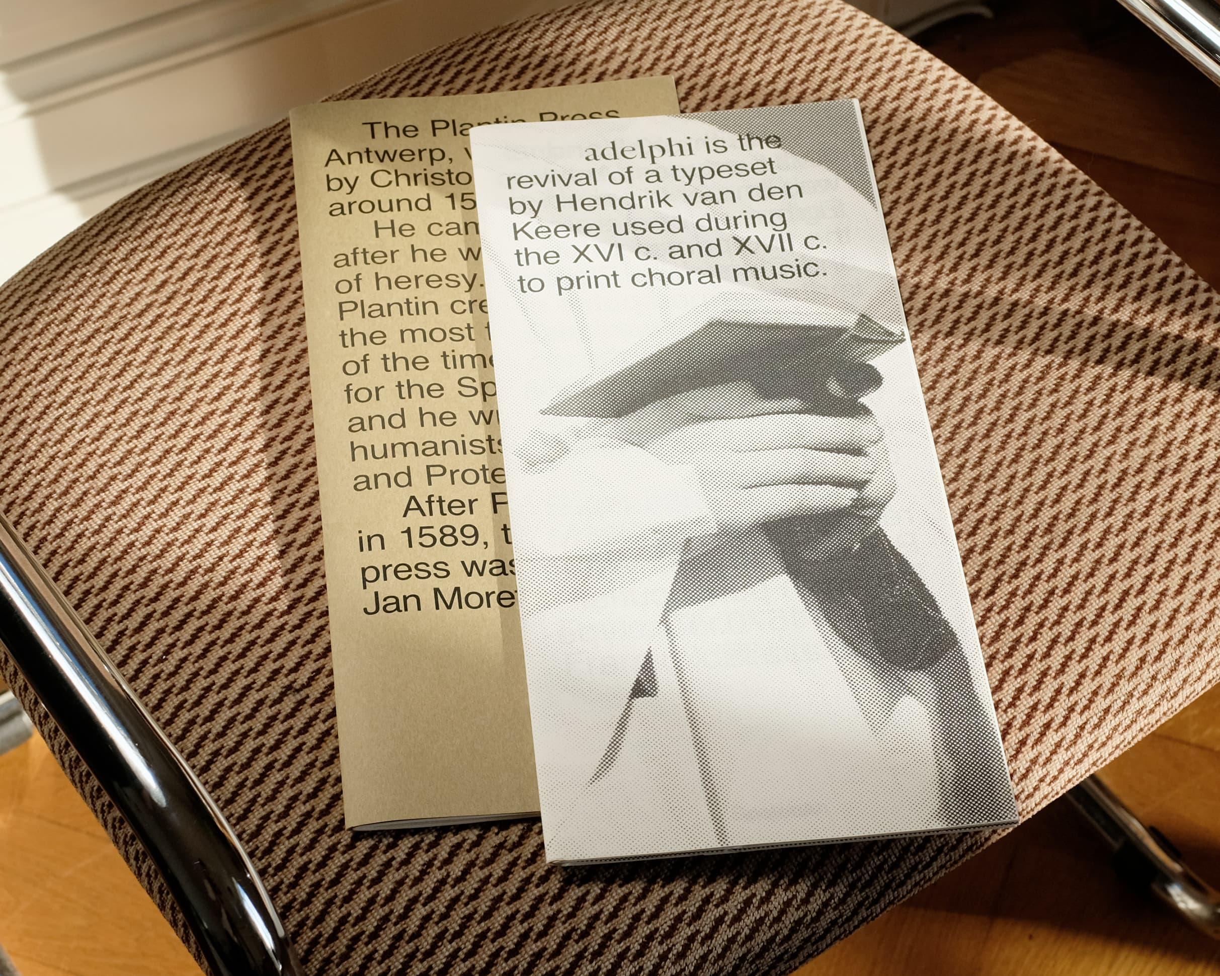 Open Adelphi publication with folded white paper forms on a chair.