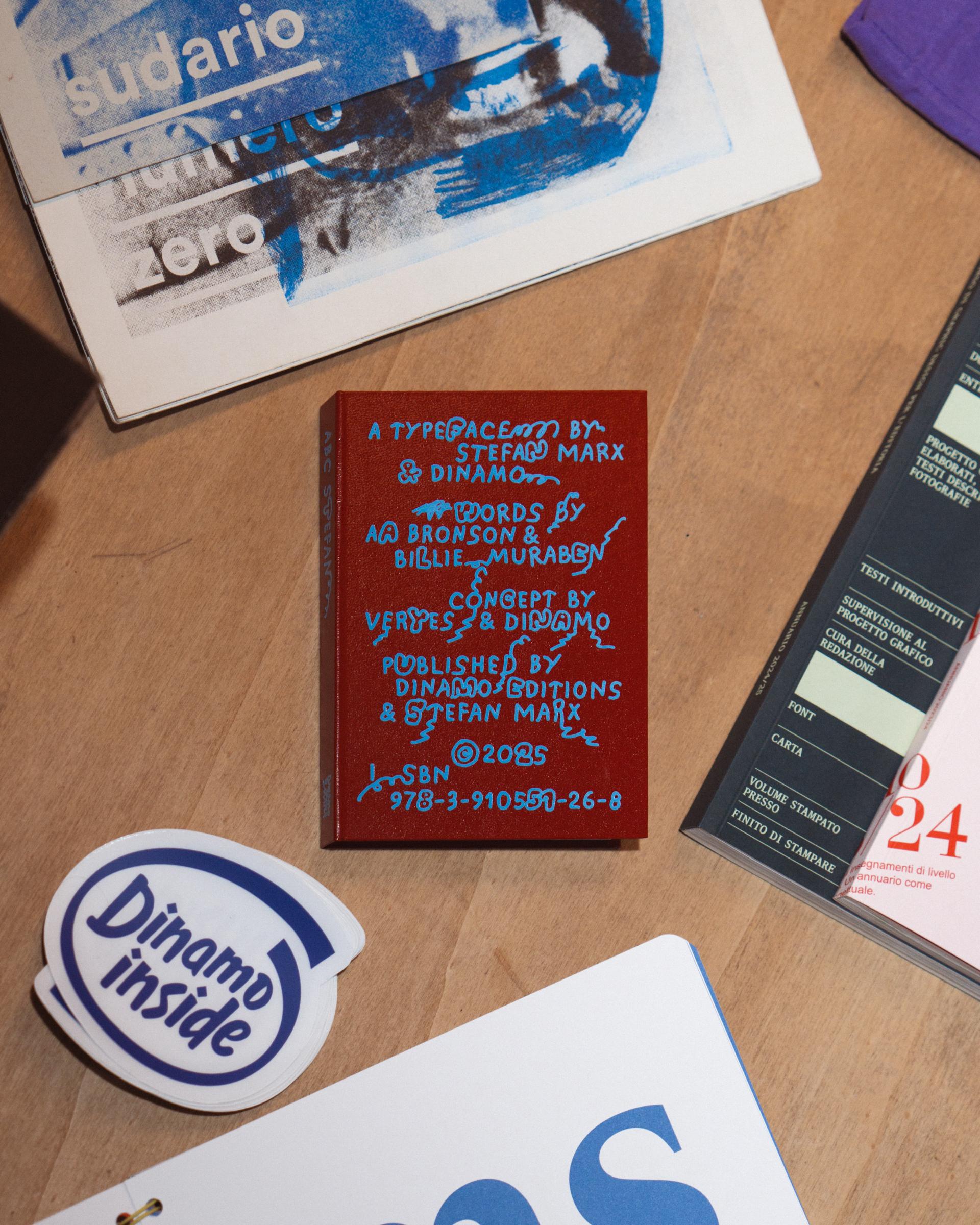 Books, printed cards and a Dinamo Inside sticker on a wooden table.