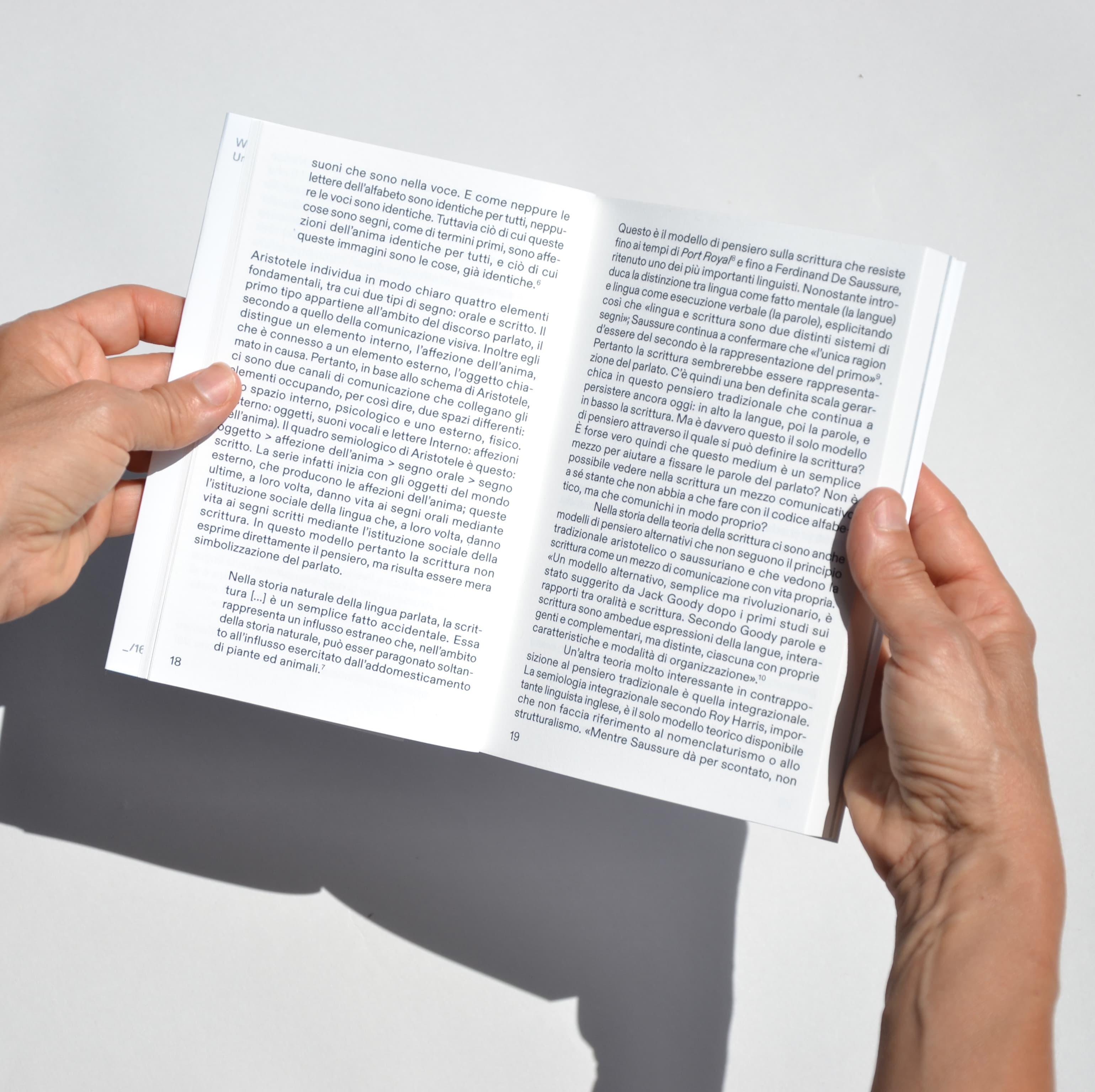 Hand holding open Write It Personal book with dense black text.