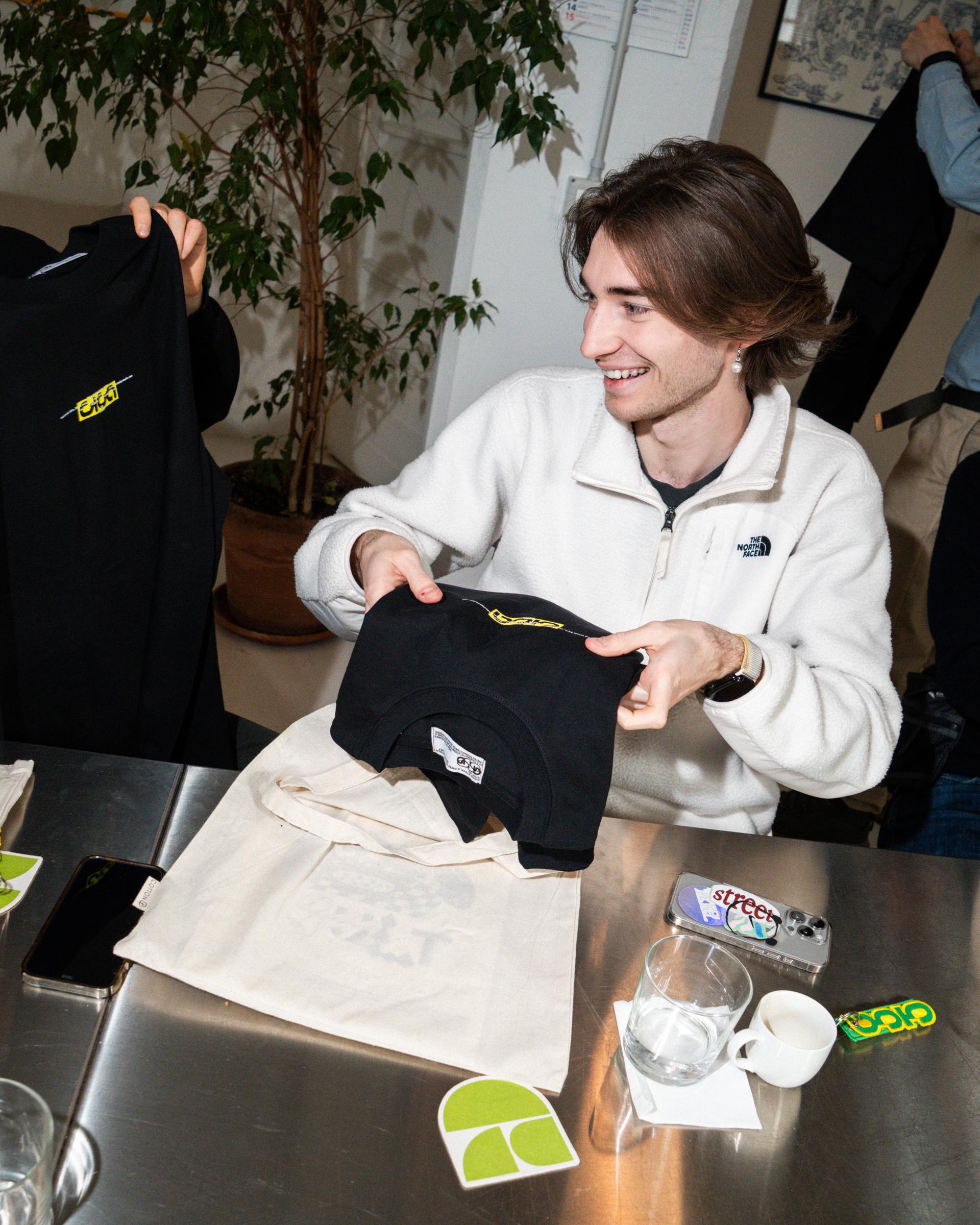 Black Giga sweatshirt and a Pittogramma tote bag on a white sofa.