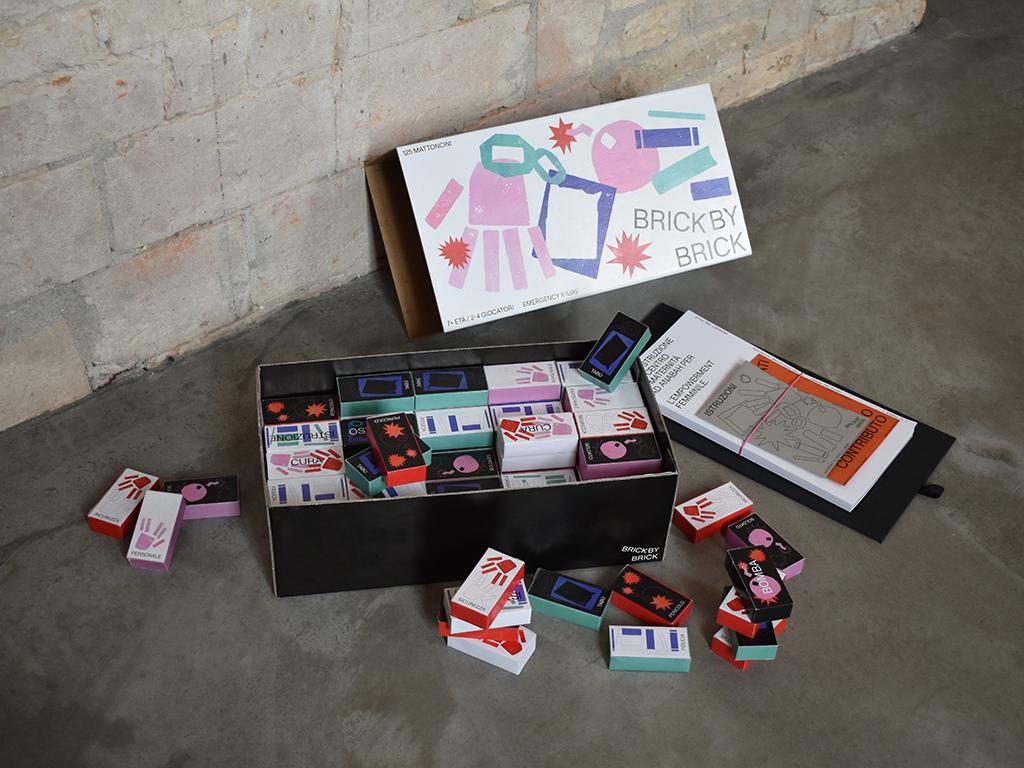 Brick by Brick box, cards and game pieces on concrete.