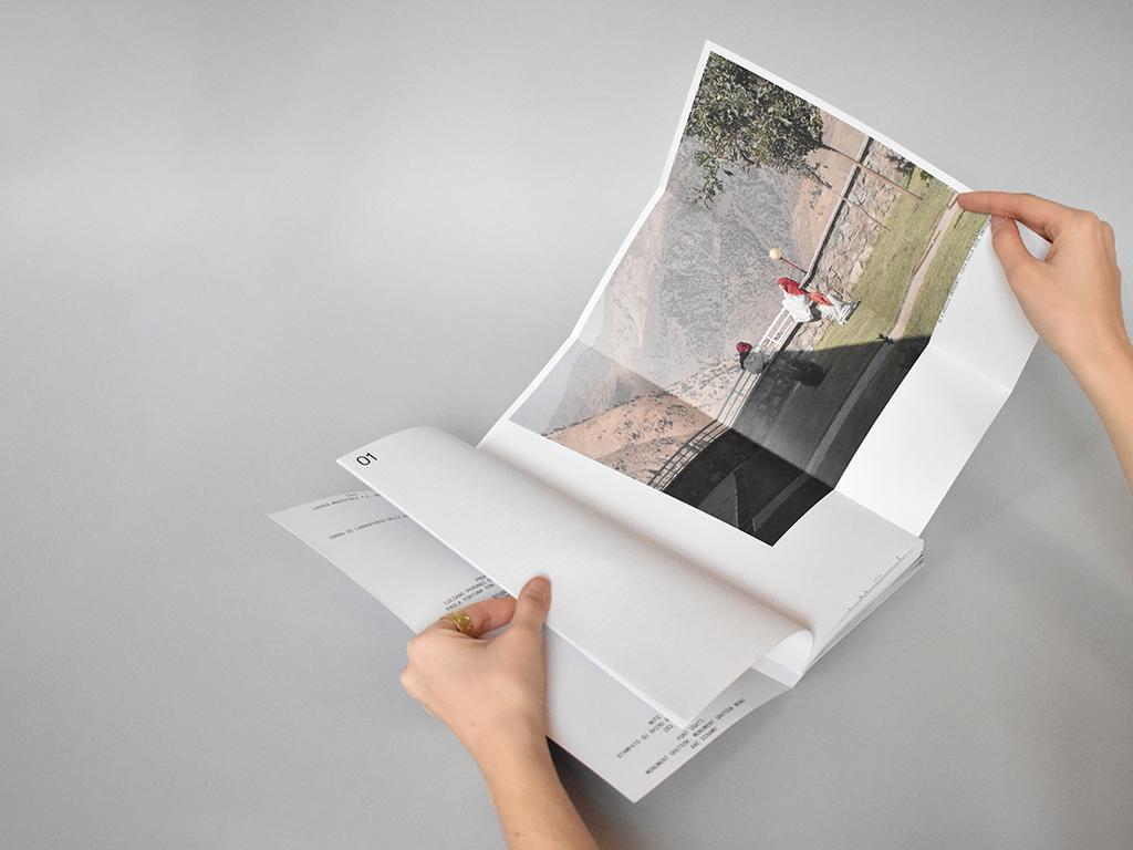 Hands opening the Brick by Brick publication to a page with a large documentary photograph.