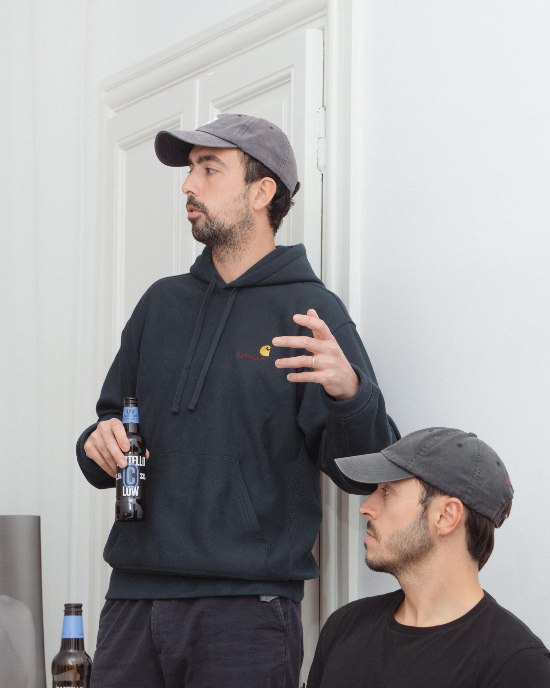 Studio Pesca host speaking with a Castello beer bottle, beside another host.