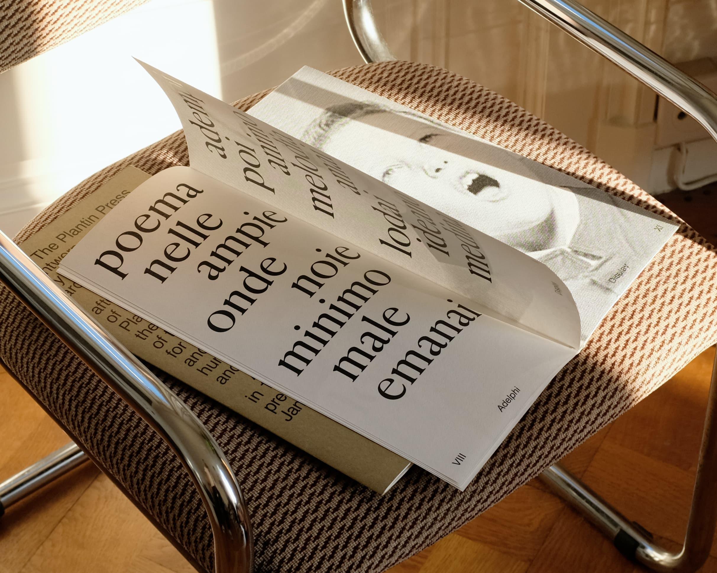Close-up of Adelphi publication pages with large serif lettering on a patterned chair.