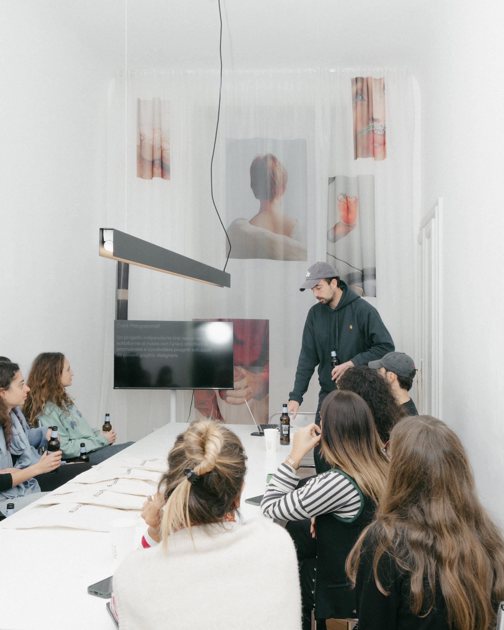 5+1 participants listening to a Studio Pesca presentation around a long table.