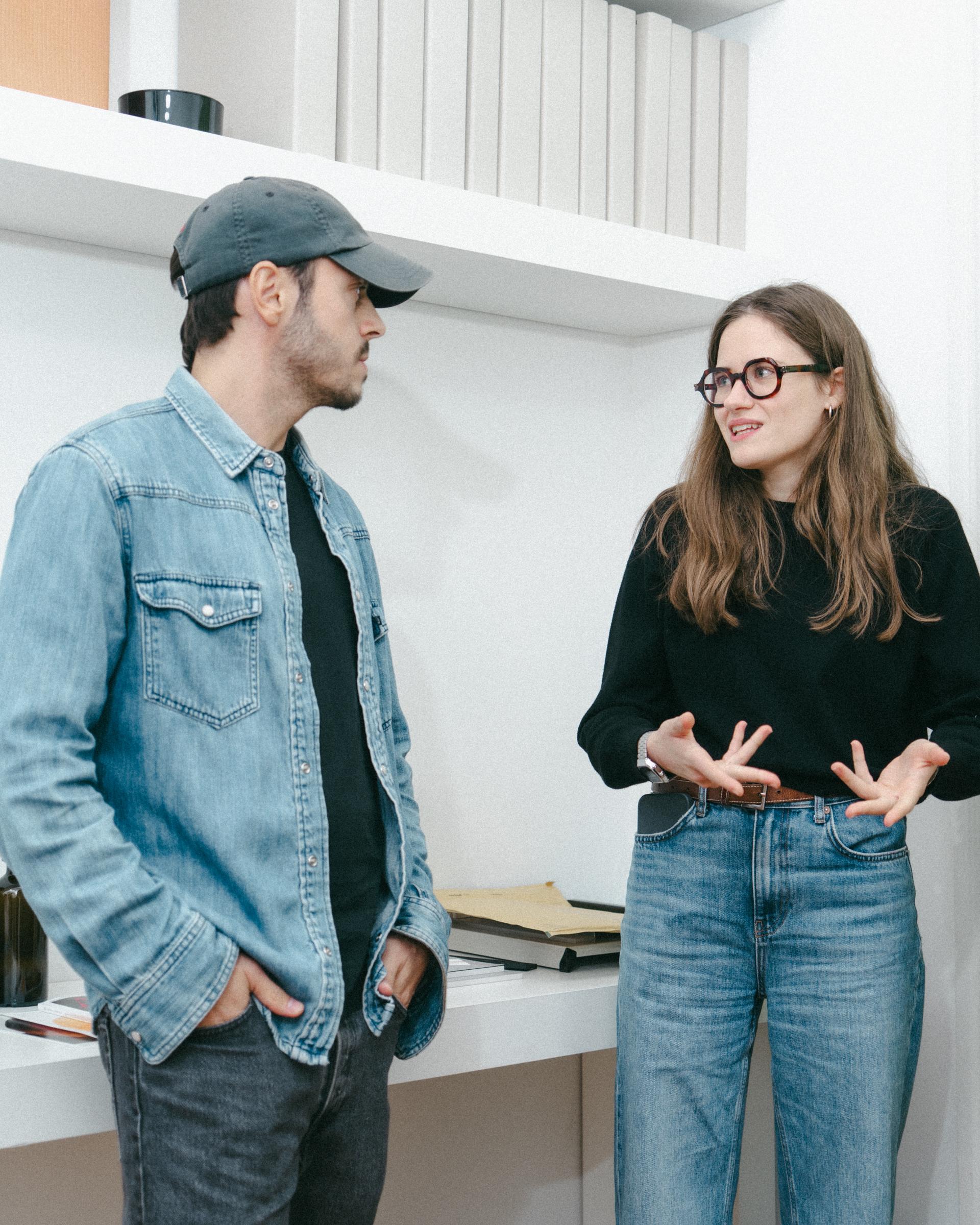 Studio Pesca hosts talking in front of a shelf of books and printed material.