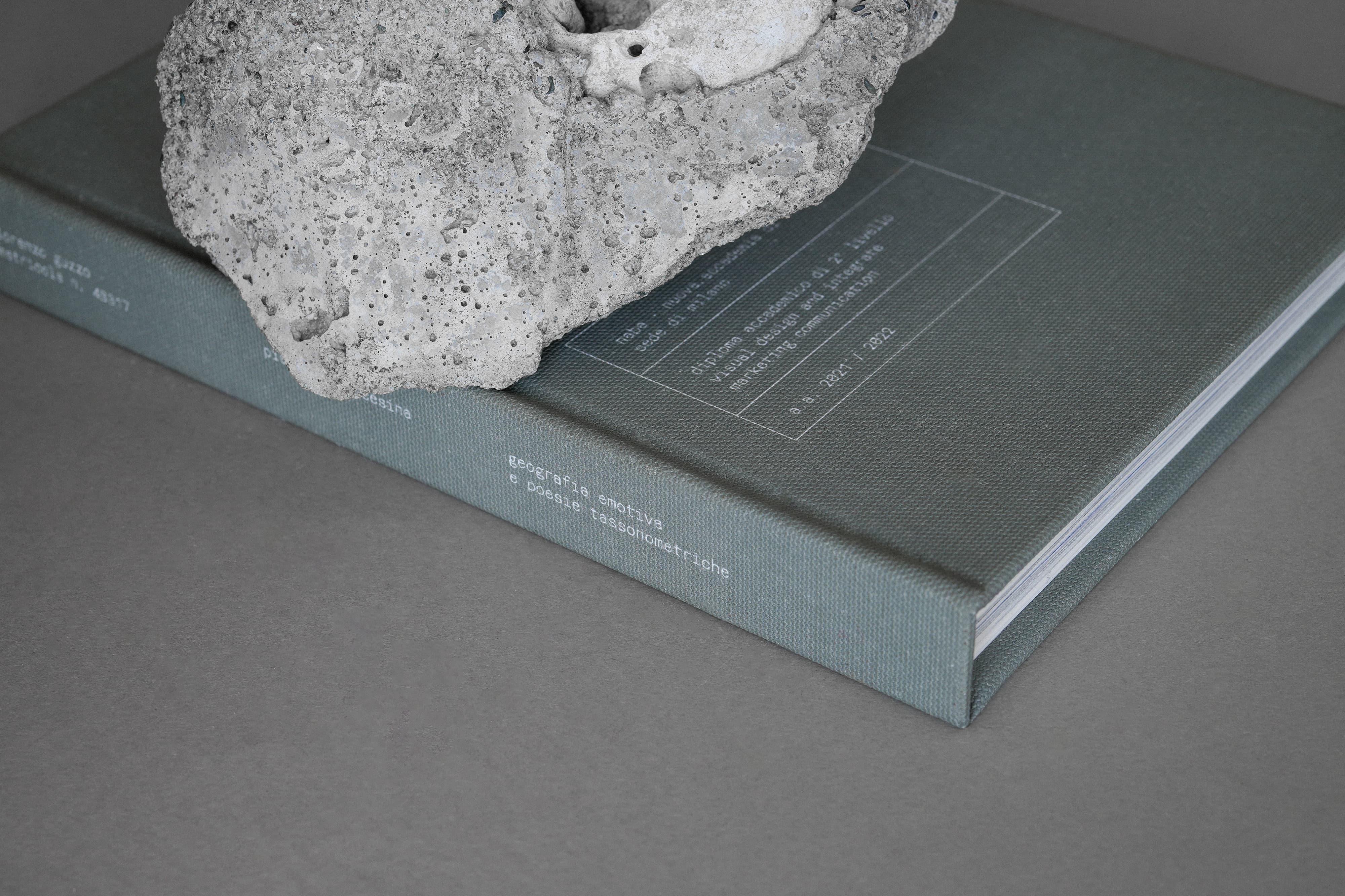 Grey Piana di Marcésina book partly covered by a white stone.