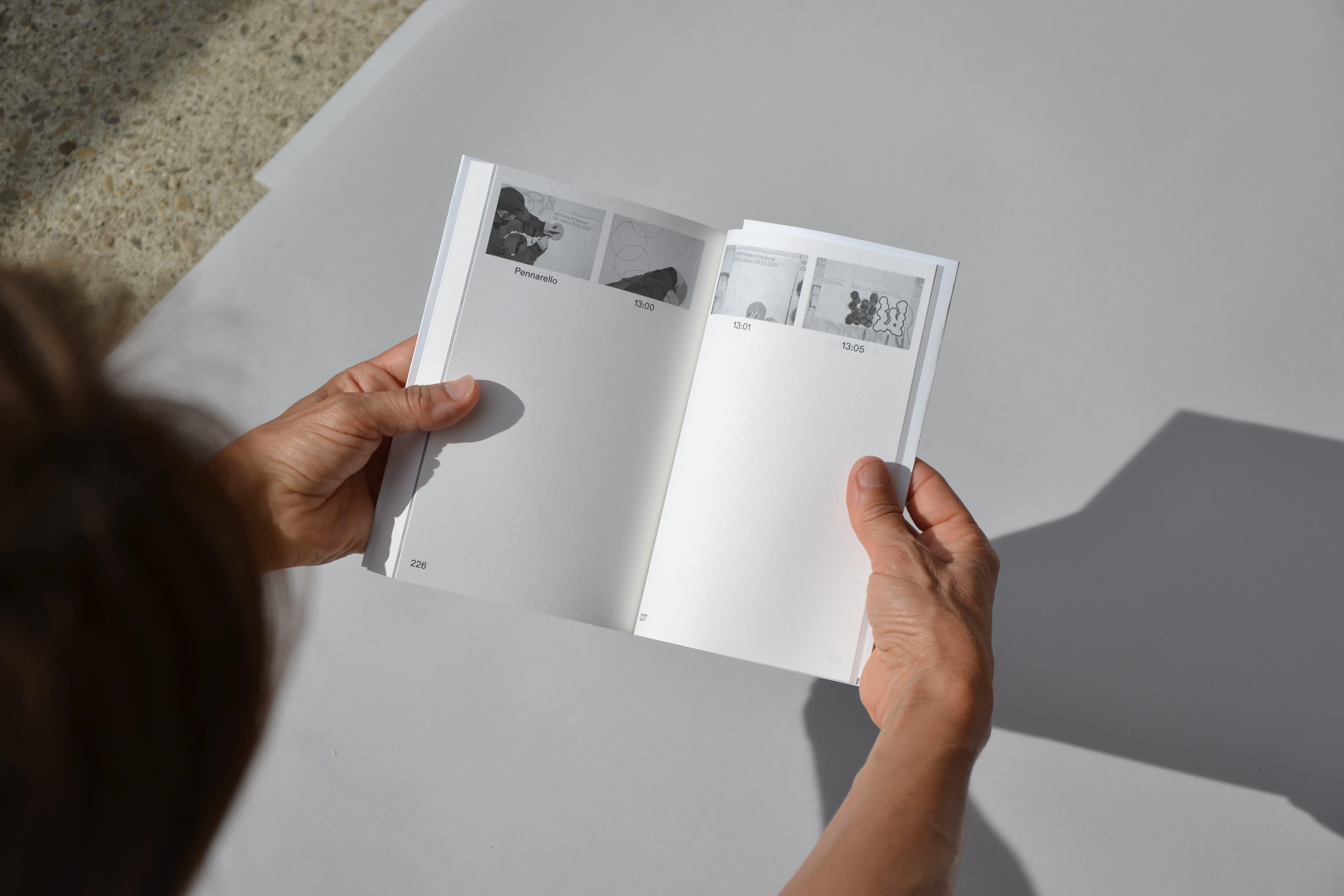 Hands holding open white Write It Personal book with small photographic panels.