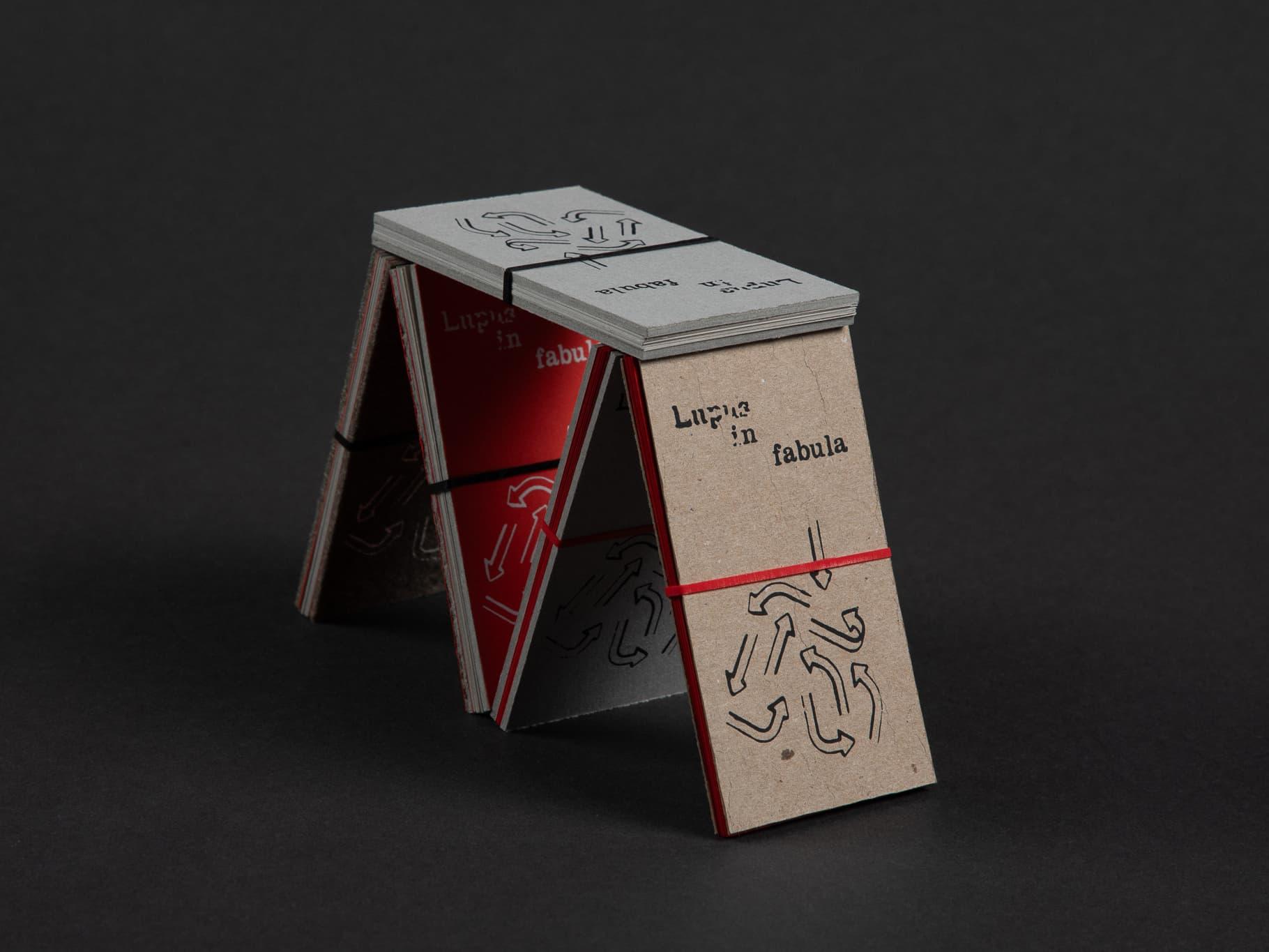 Folded Omne quod non mutat nox publication standing like a small easel.