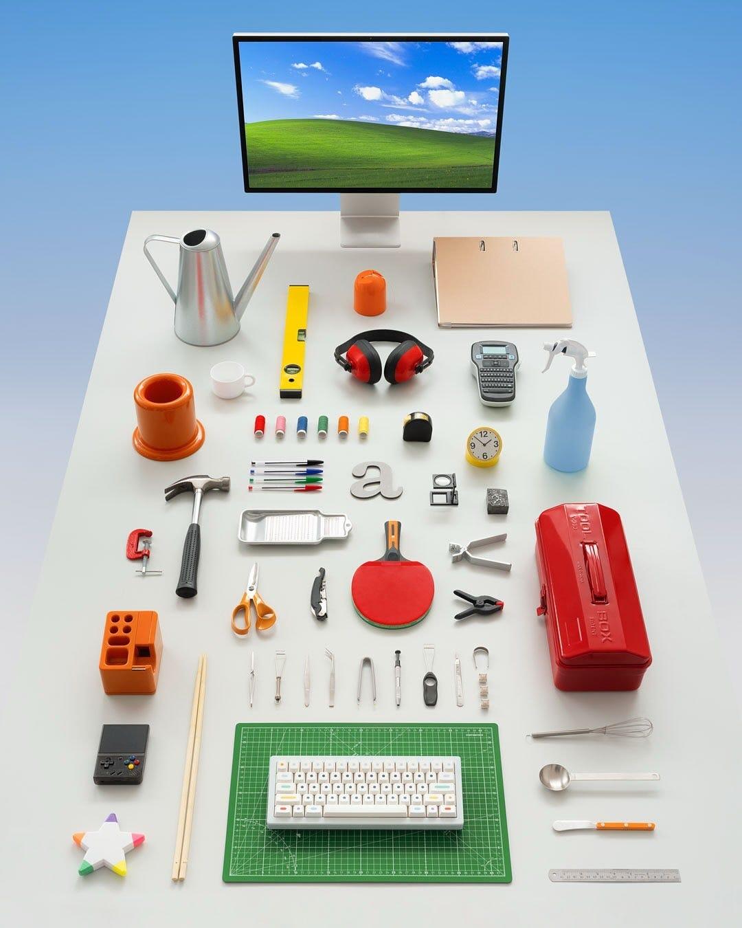 Overhead view of the Aeiou Desk poster: a white desk under a Windows XP screen, arranged with tools, stationery and a keyboard.