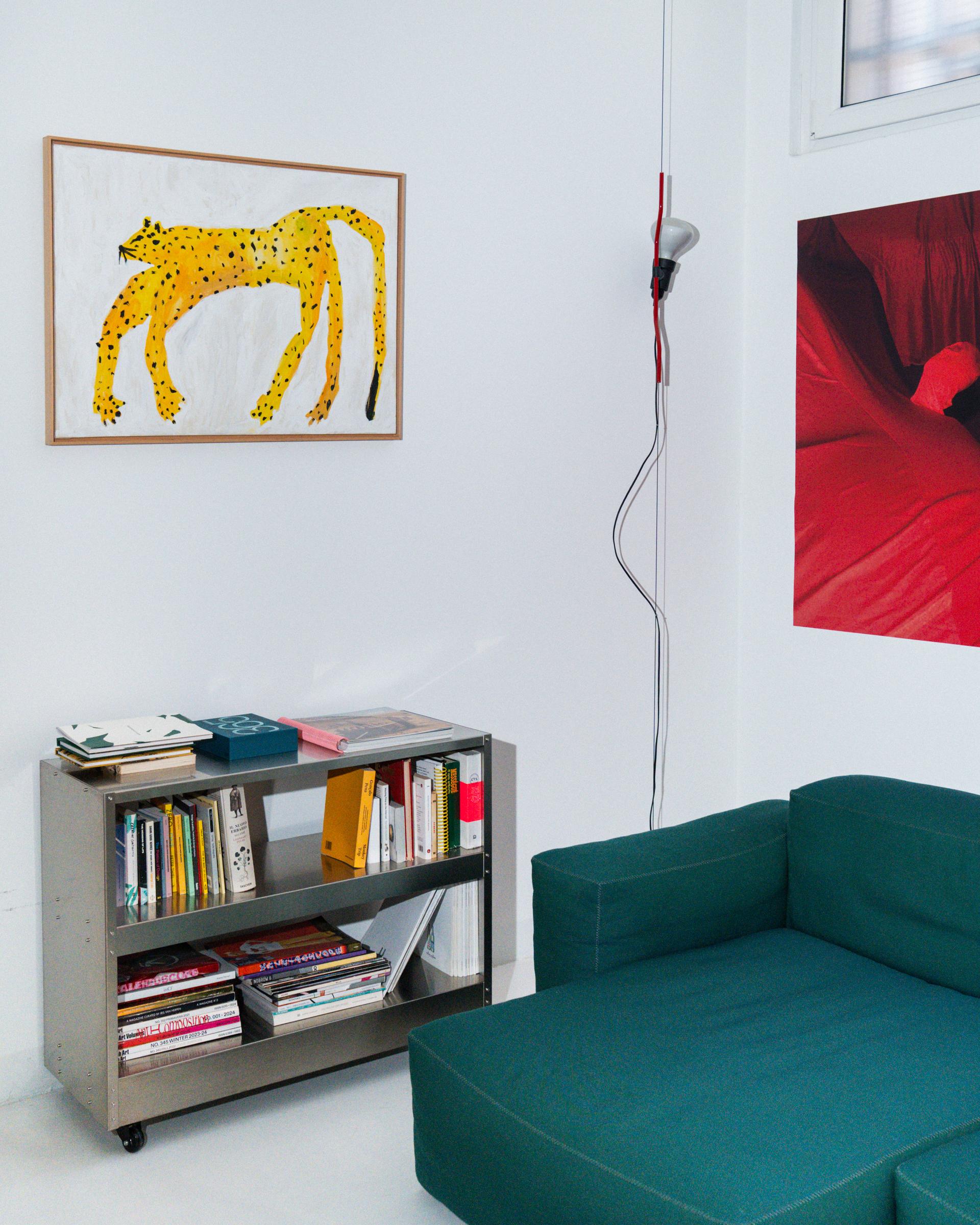 Giga studio interior with a teal sofa, bookshelves and framed works.