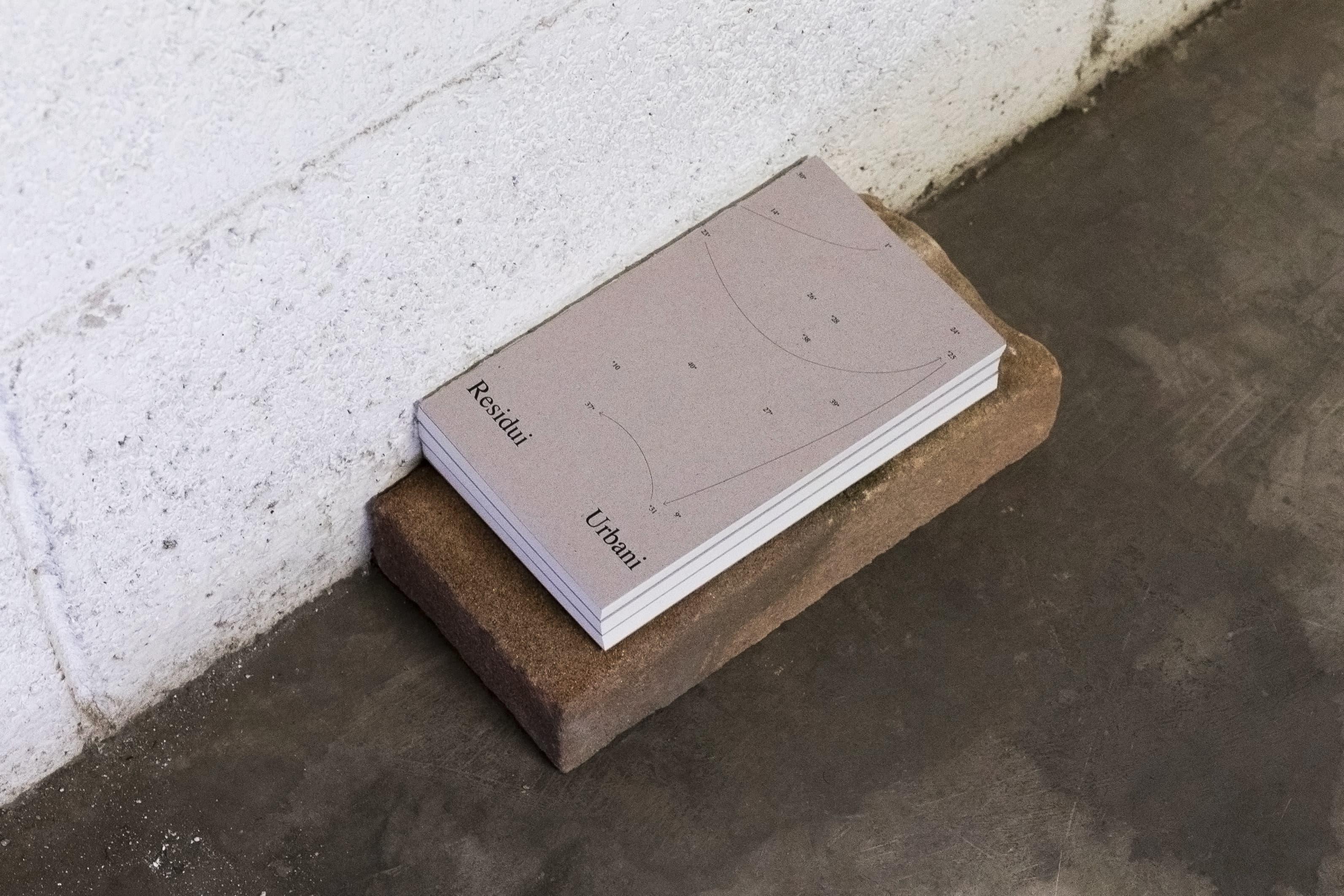 Pale pink Residui Urbani book on a concrete block.