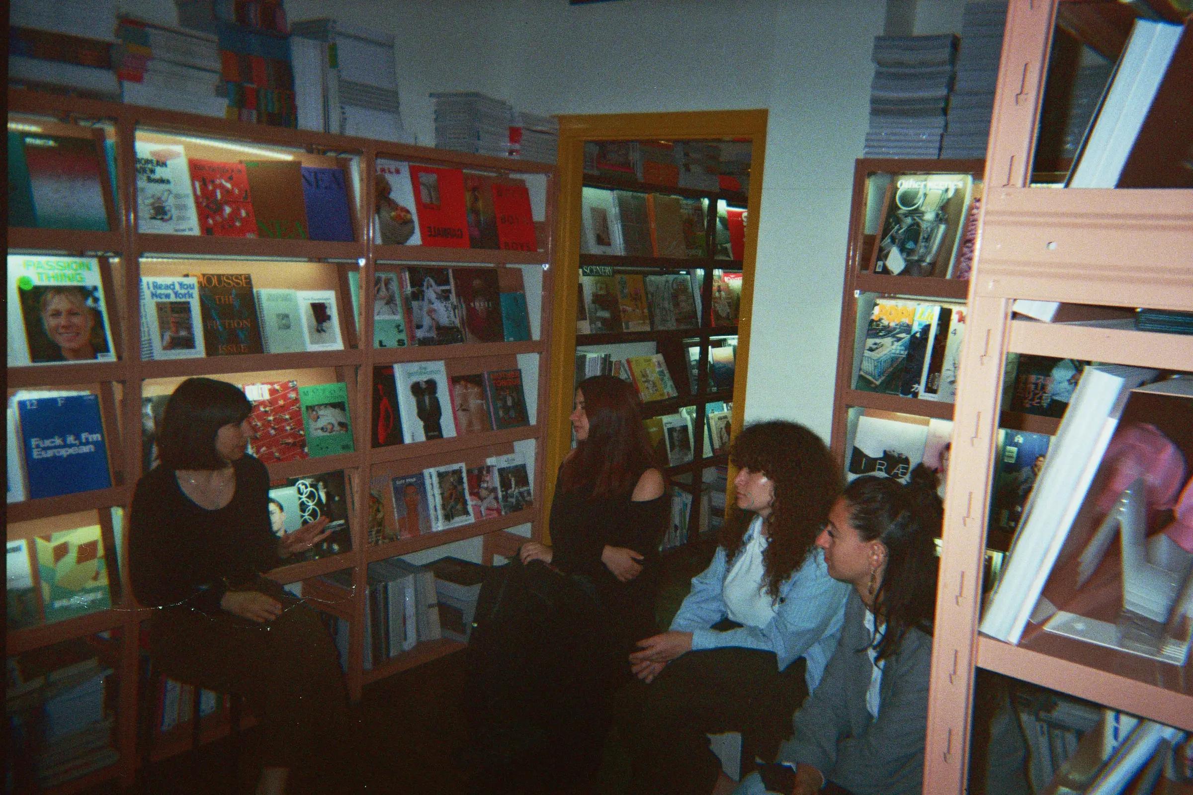 Three people sitting in front of shelves of independent and collectible magazines at Frab's Magazines & More.