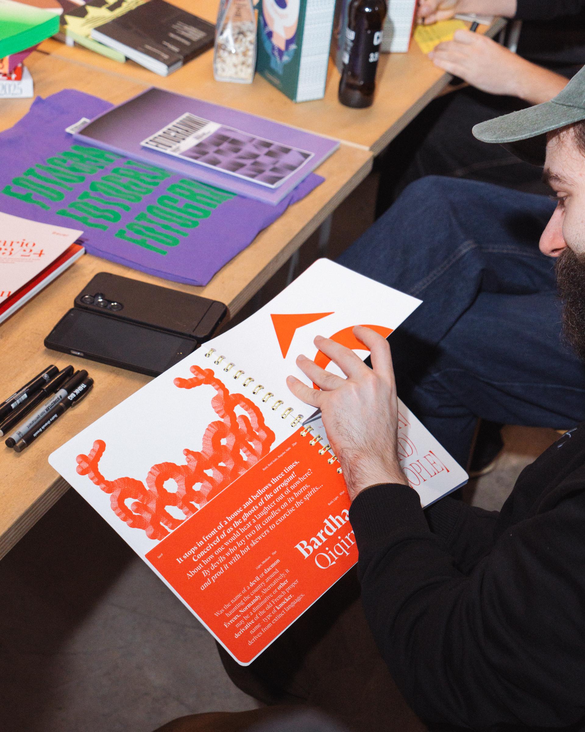 Attendee looking through an illustrated book beside printed matter and markers.