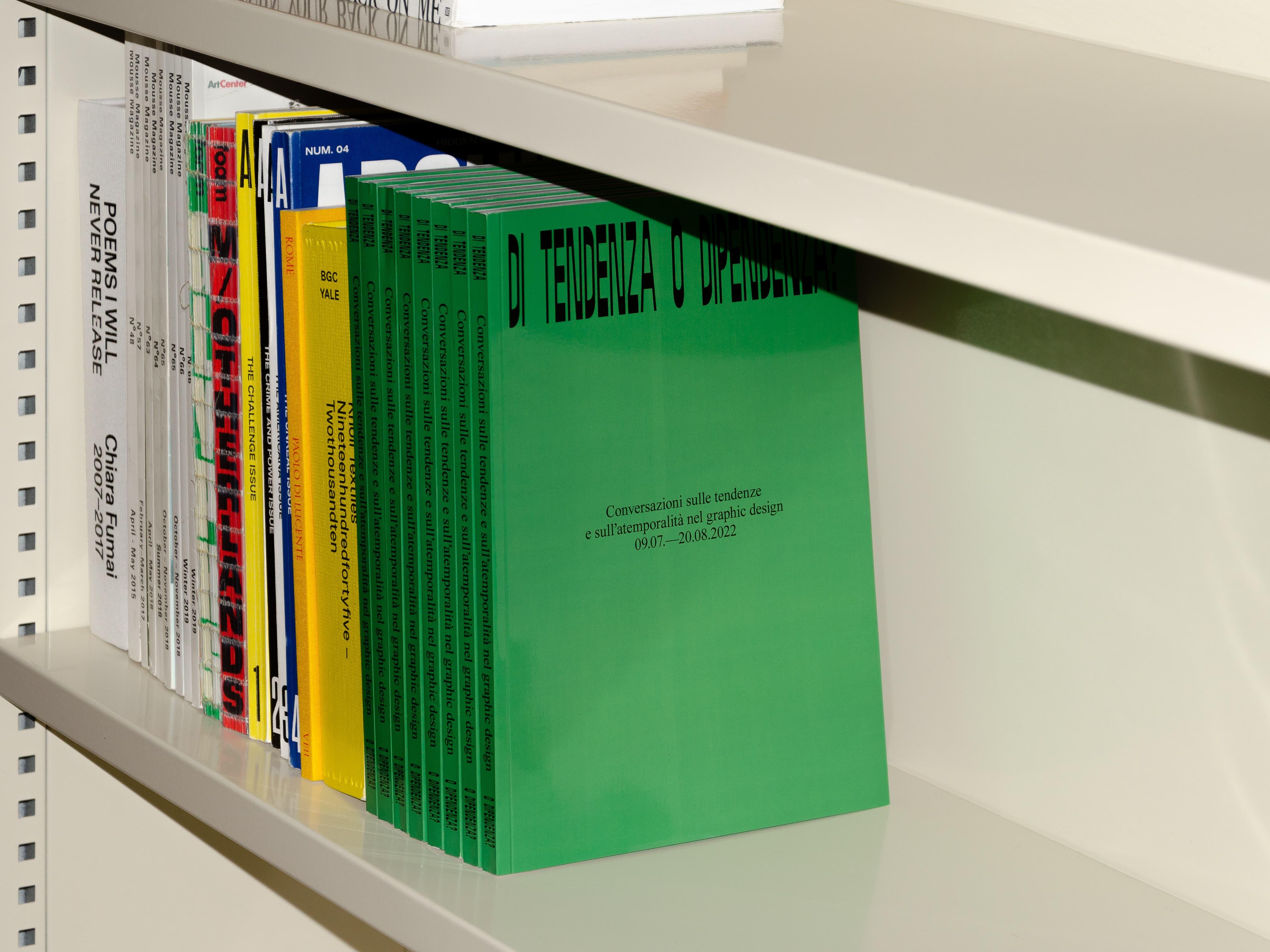 White shelf of books with a row of bright green volumes.