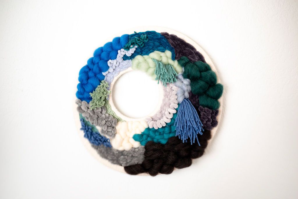 Round fiber wreath in blues, teal, white and black textured yarn