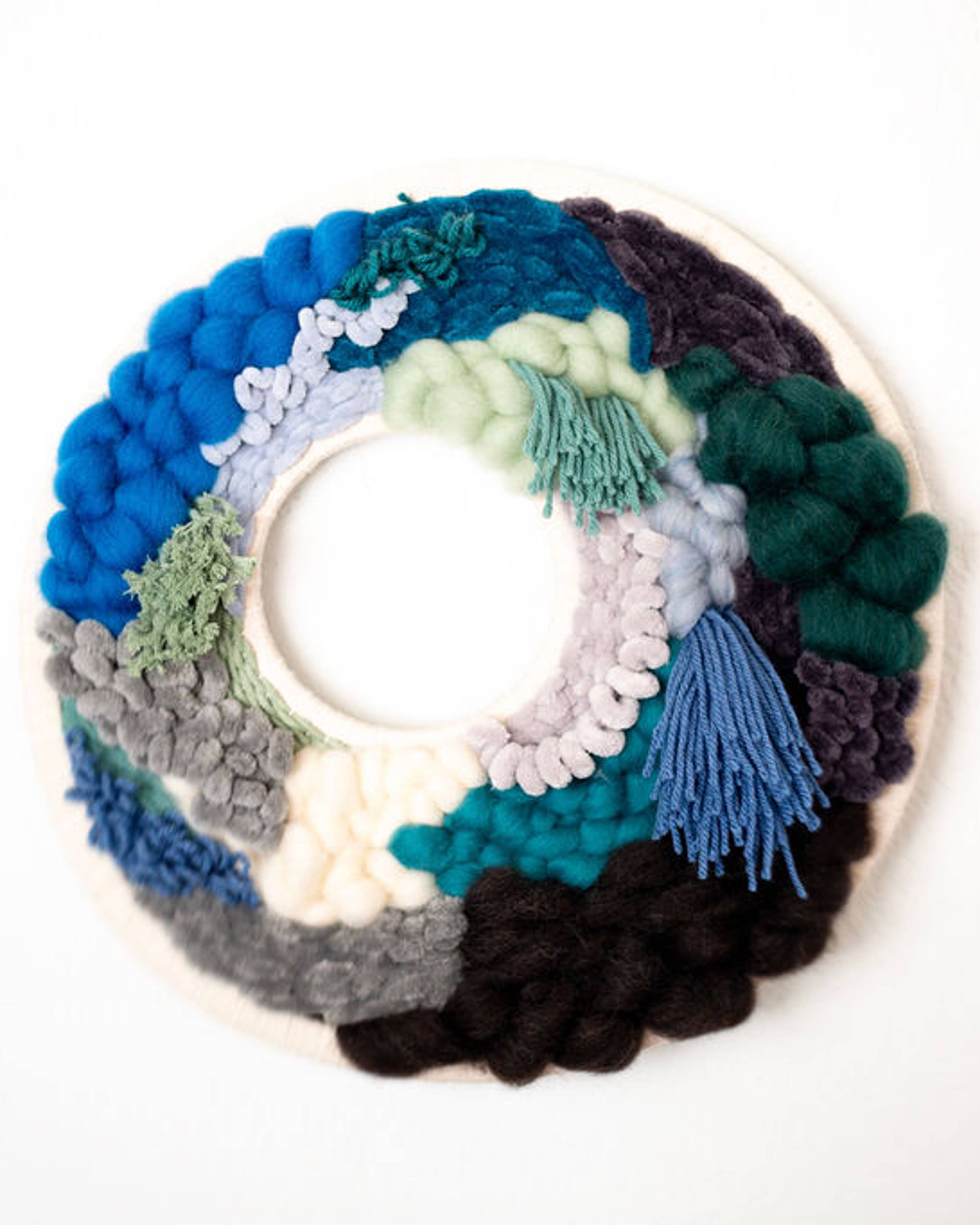 Round fiber wreath in blues, teal, white and black textured yarn