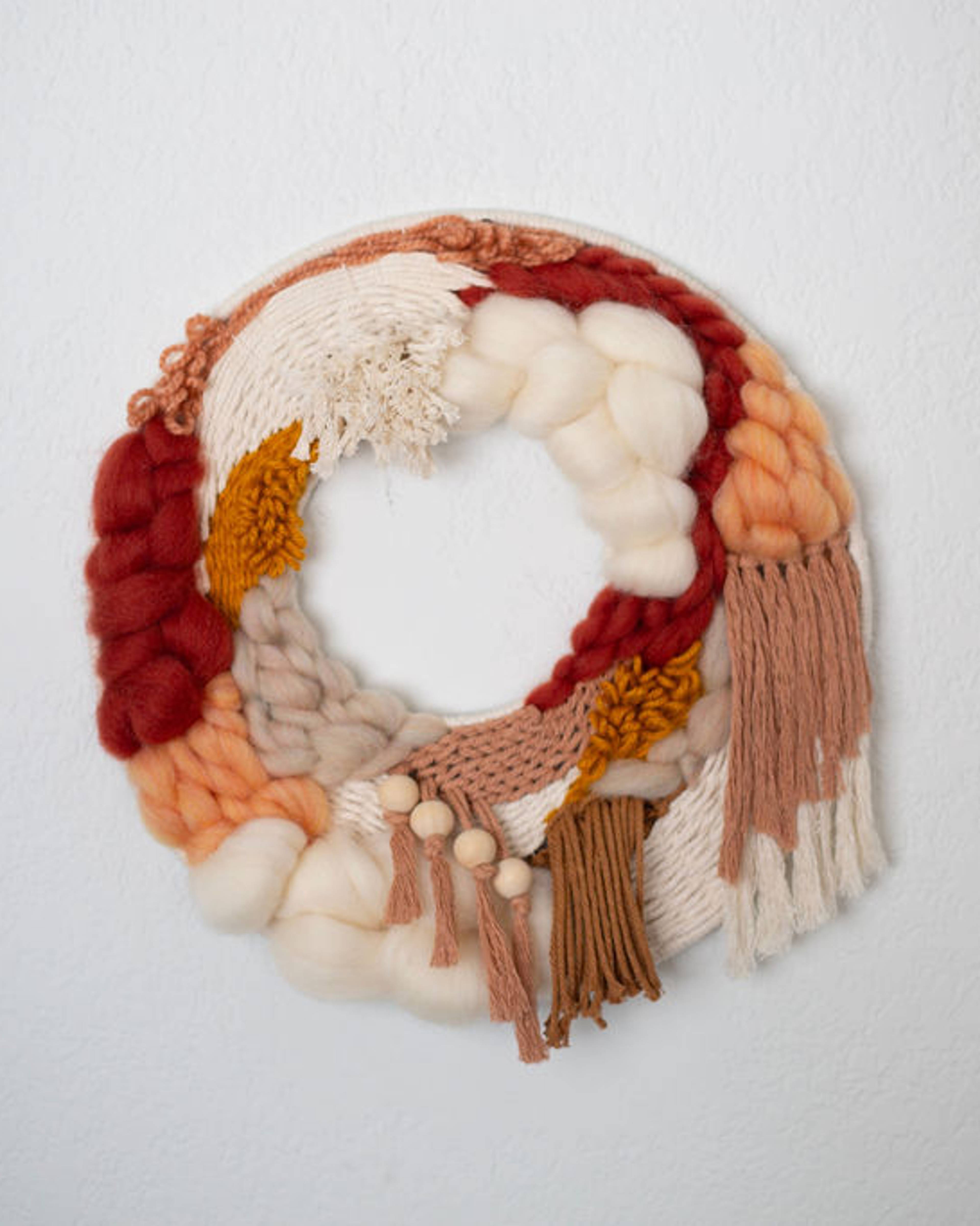 Round fiber wreath in red, rust, peach and cream with fringe