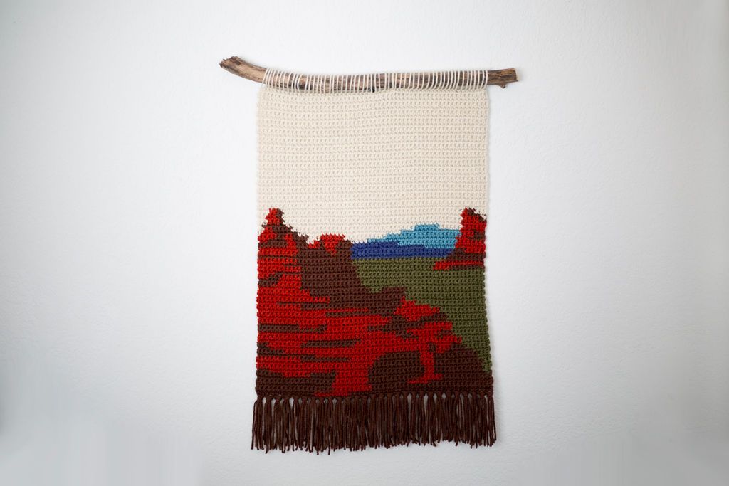 Crochet tapestry of red mesas under a pale sky, with brown fringe