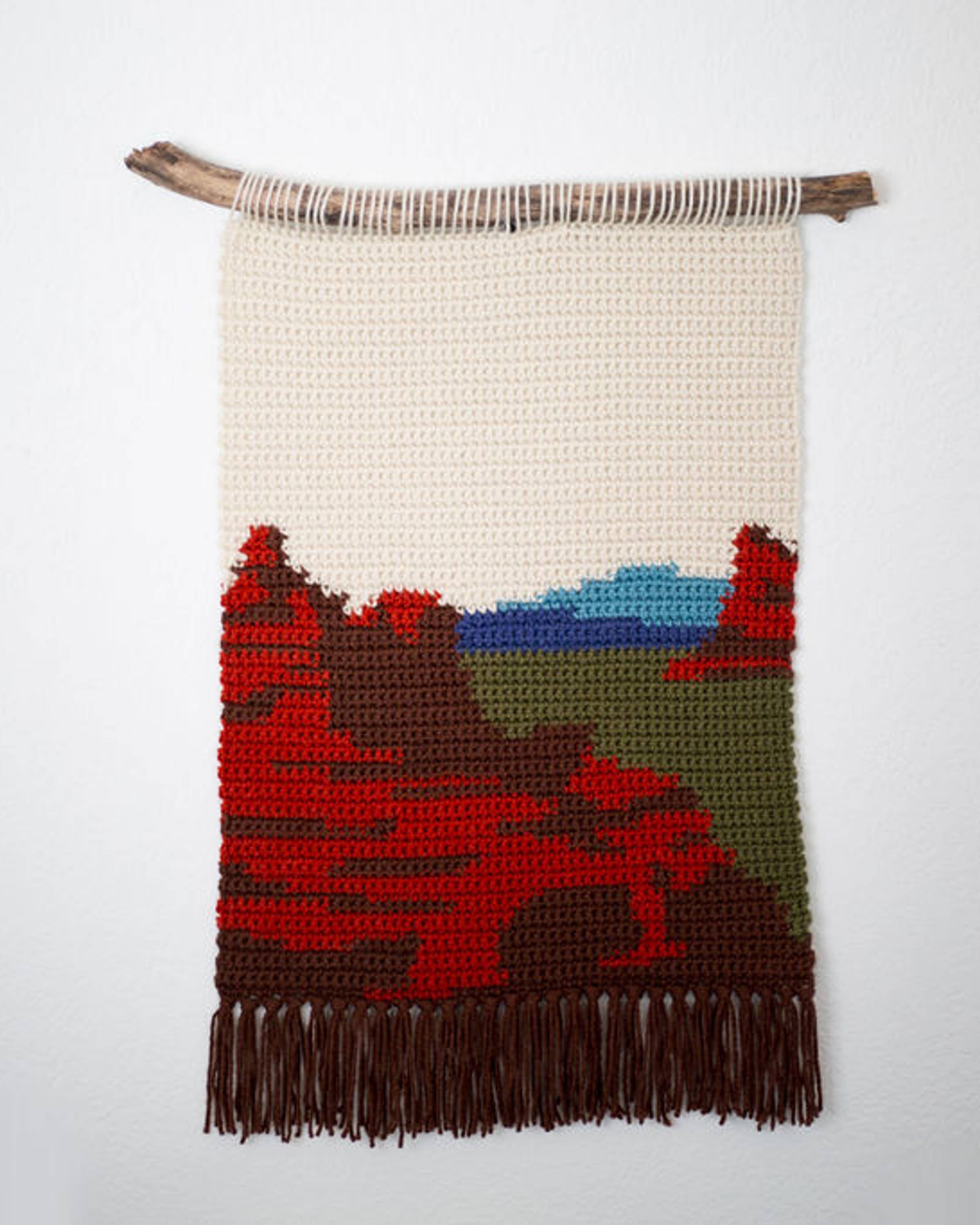 Crochet tapestry of red mesas under a pale sky, with brown fringe