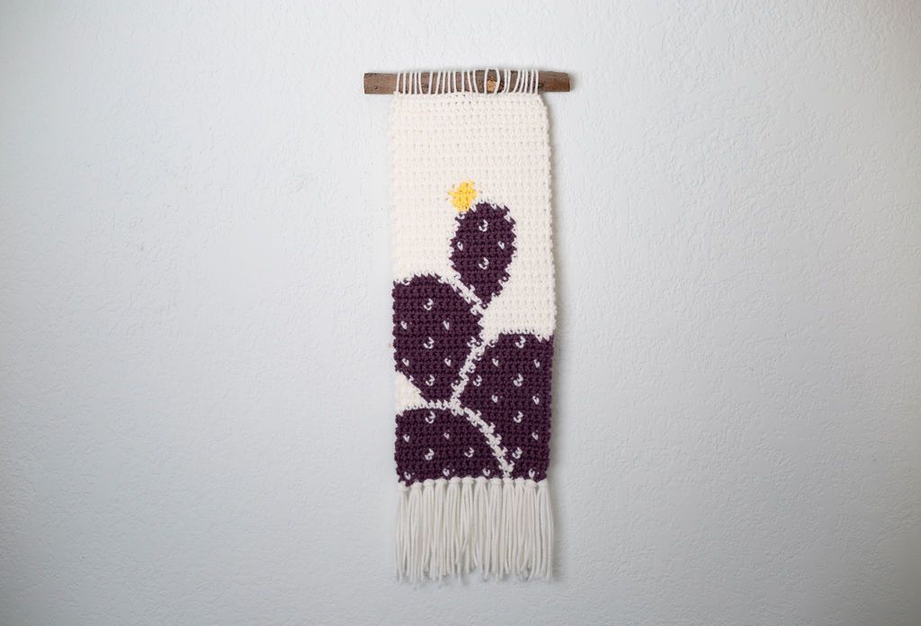 Narrow cream crochet tapestry with a purple prickly pear cactus and a small yellow bloom