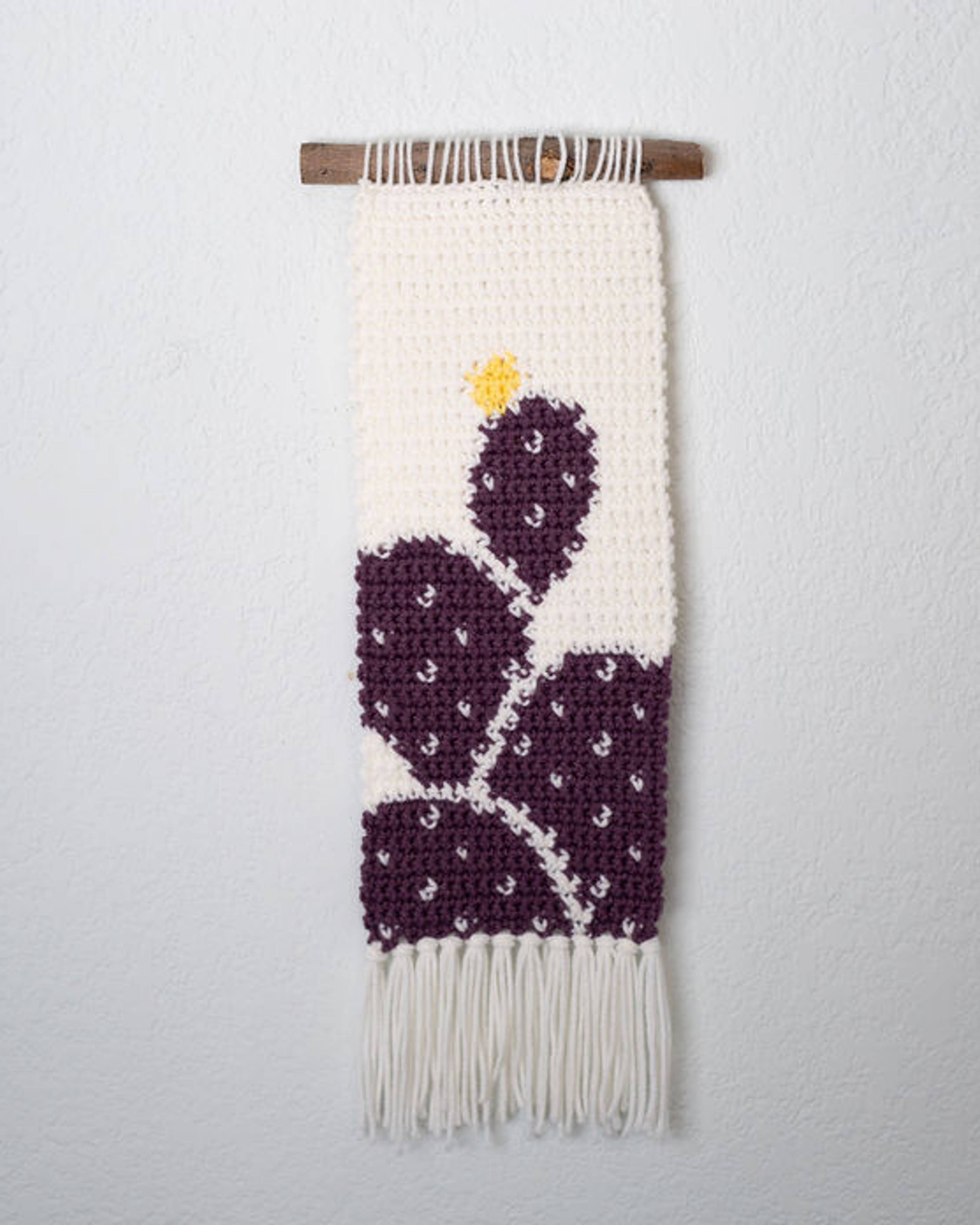 Narrow cream crochet tapestry with a purple prickly pear cactus and a small yellow bloom