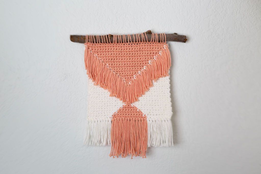 Peach and cream wall hanging on a driftwood branch with a long peach tassel