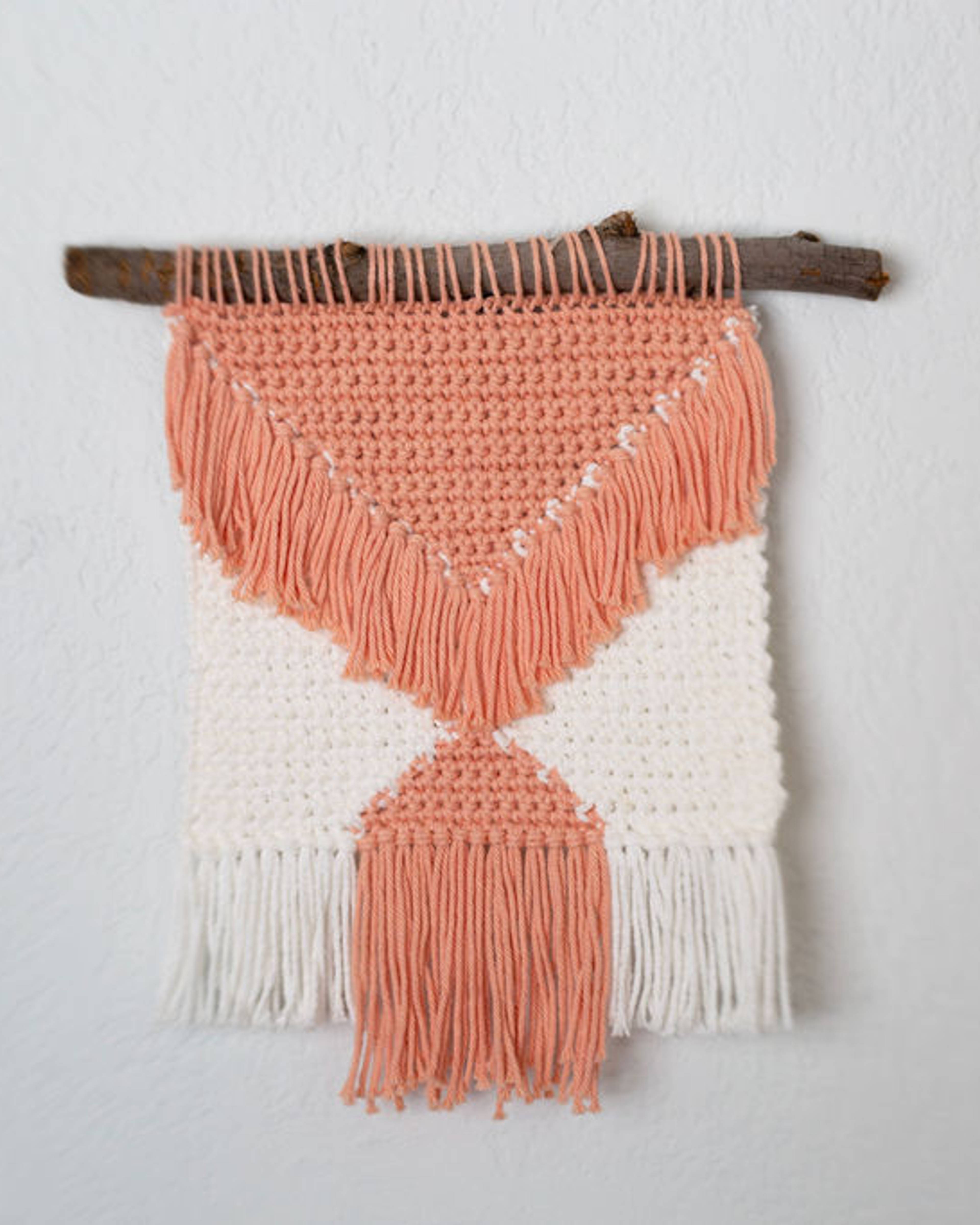 Peach and cream wall hanging on a driftwood branch with a long peach tassel