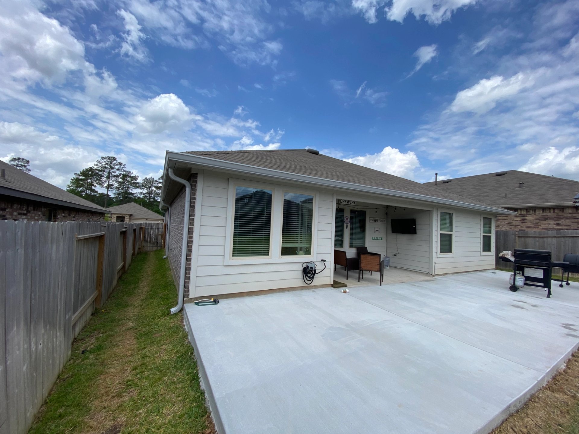 Light gray seamless gutter and matching downspouts around a covered patio on a Magnolia home