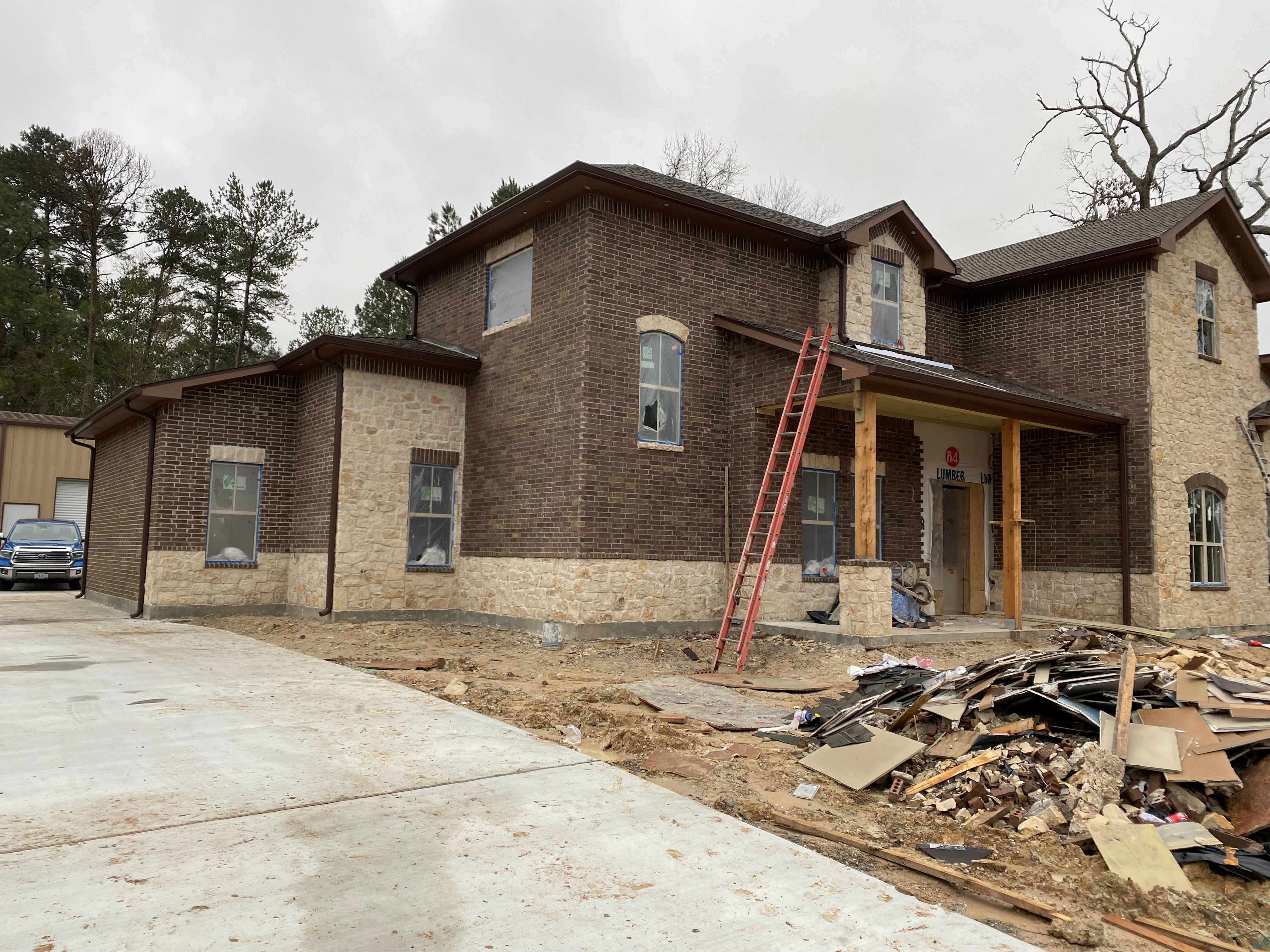 Brown seamless gutters and downspouts on the side of a new two-story brick home in Conroe