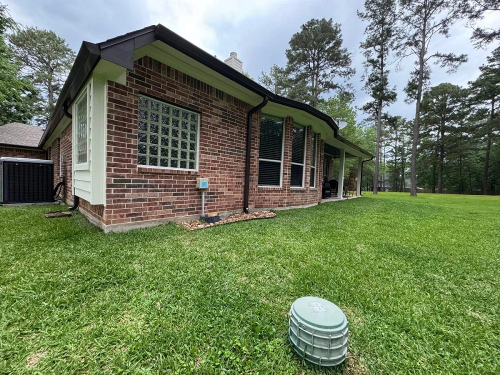 Black gutters and downspouts along the rear brick walls beside the covered patio