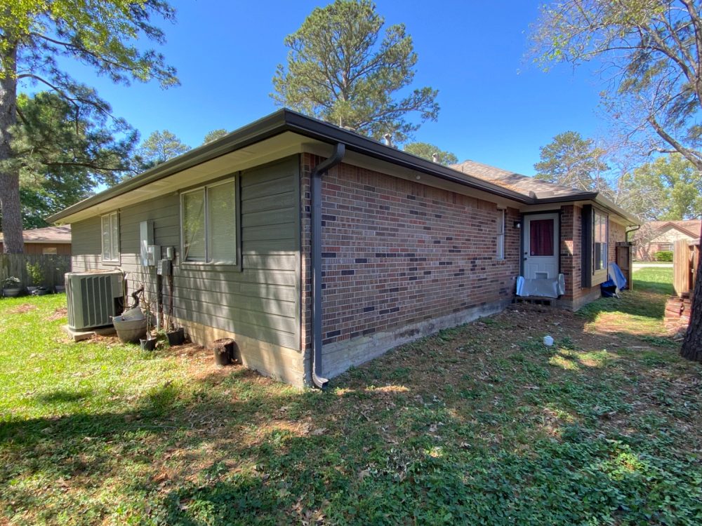 Light bronze seamless gutter and matching downspout around the rear corner of a Montgomery brick home