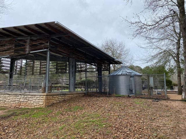 Open-sided Conroe park pavilion with a Galvalume box gutter and metal rainwater cistern beside the roofline