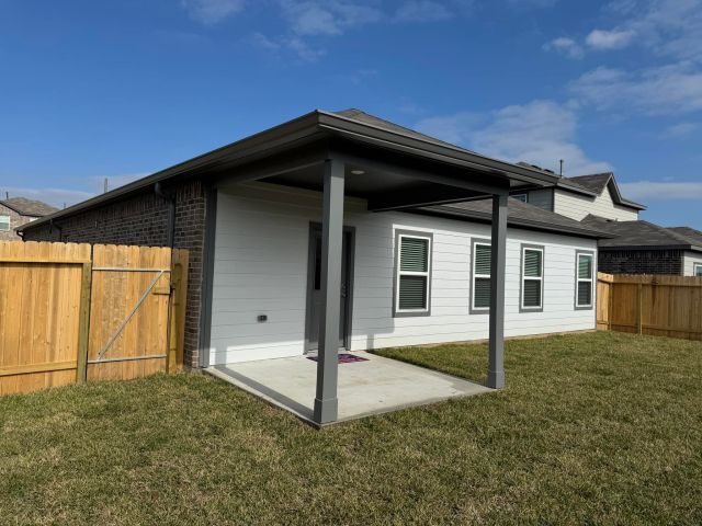 Dark gray seamless gutter and downspout around the covered back patio of a Navasota home