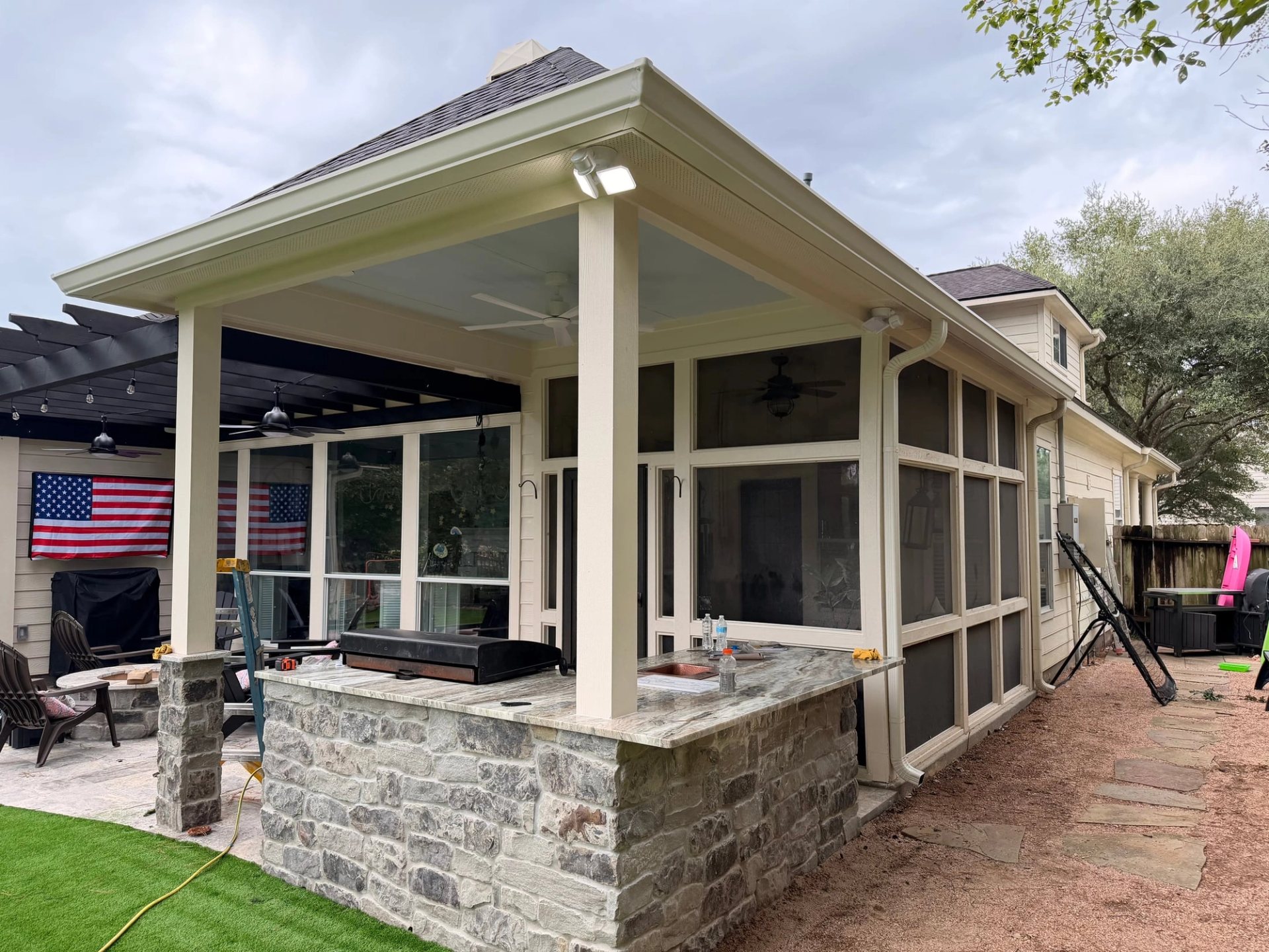 Cameo gutters on a covered patio extension with a screened room and stone outdoor kitchen in Sterling Ridge