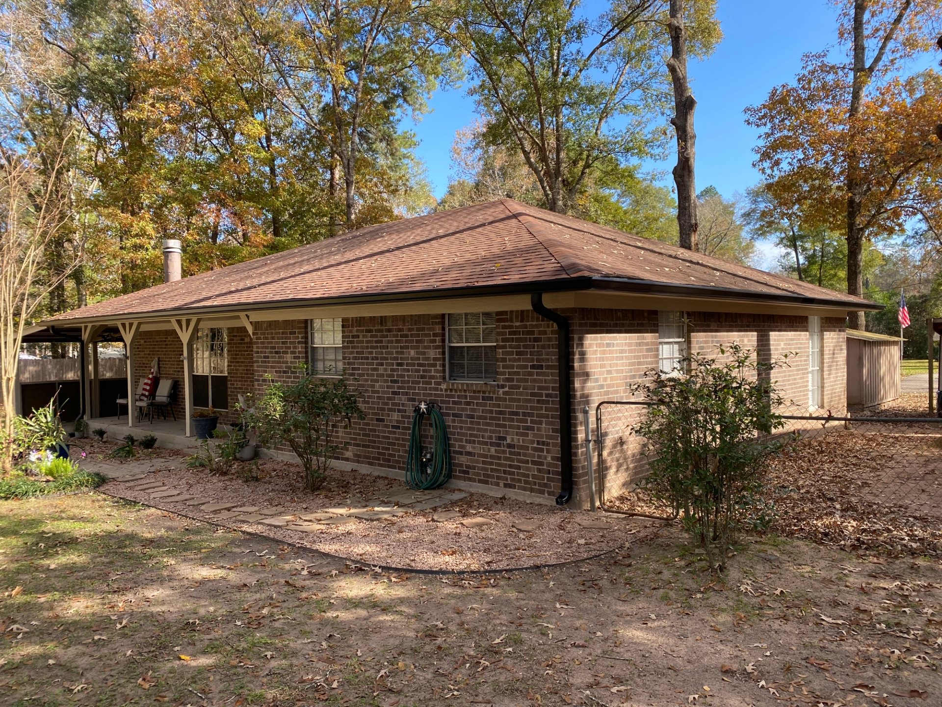 Black seamless gutters and a matching corner downspout on a single-story Conroe brick home