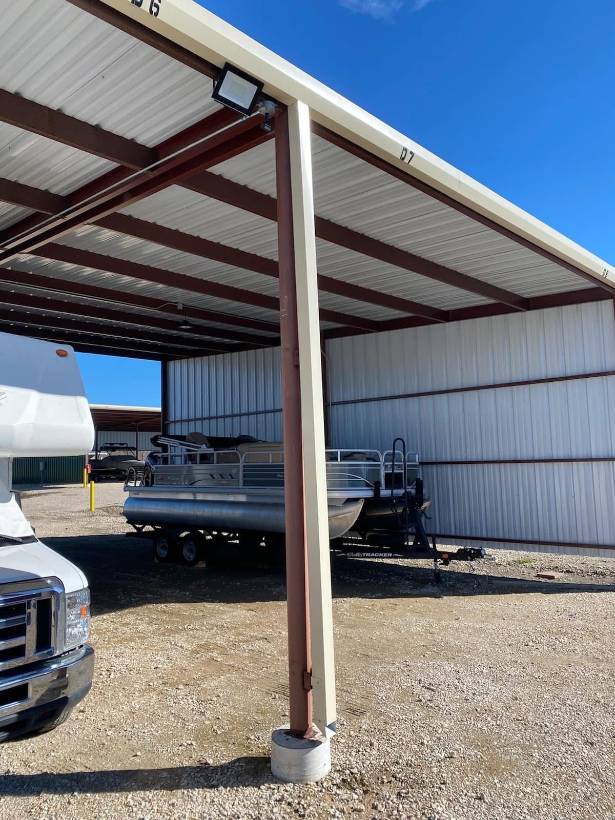 Beige 4-by-4 steel downspout running beside a brown support column on a commercial metal awning in Willis