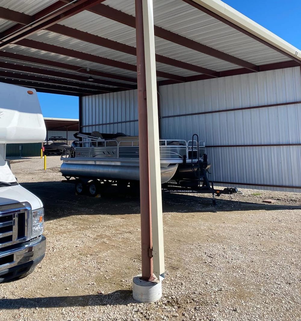 Beige 4-by-4 steel downspout running beside a brown support column on a commercial metal awning in Willis