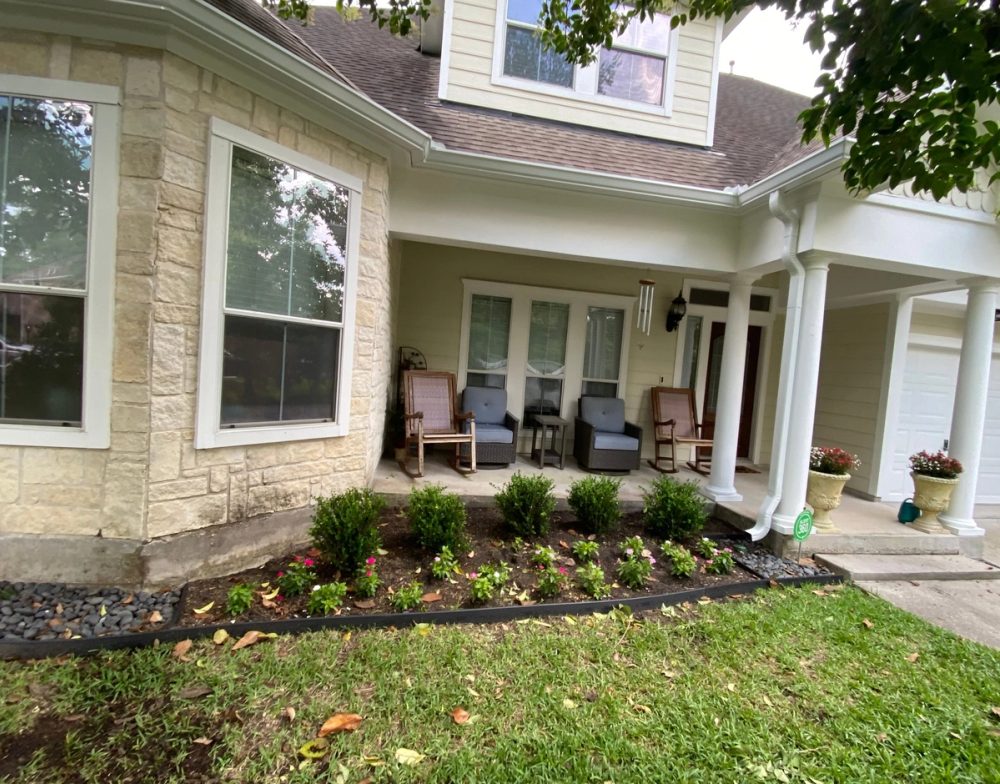 White 6-inch gutters along the stone bay window and covered front porch of a two-story Sterling Ridge home