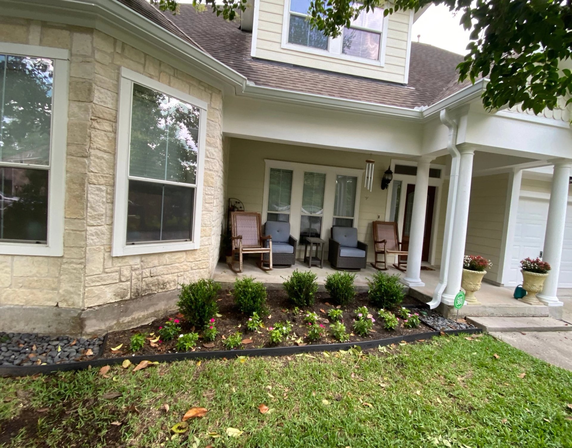 White 6-inch gutters along the stone bay window and covered front porch of a two-story Sterling Ridge home