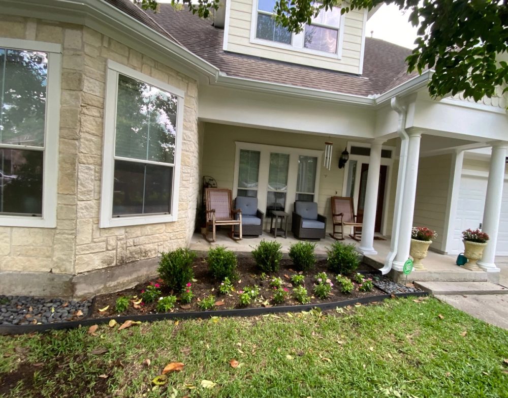 White 6-inch gutters along the stone bay window and covered front porch of a two-story Sterling Ridge home