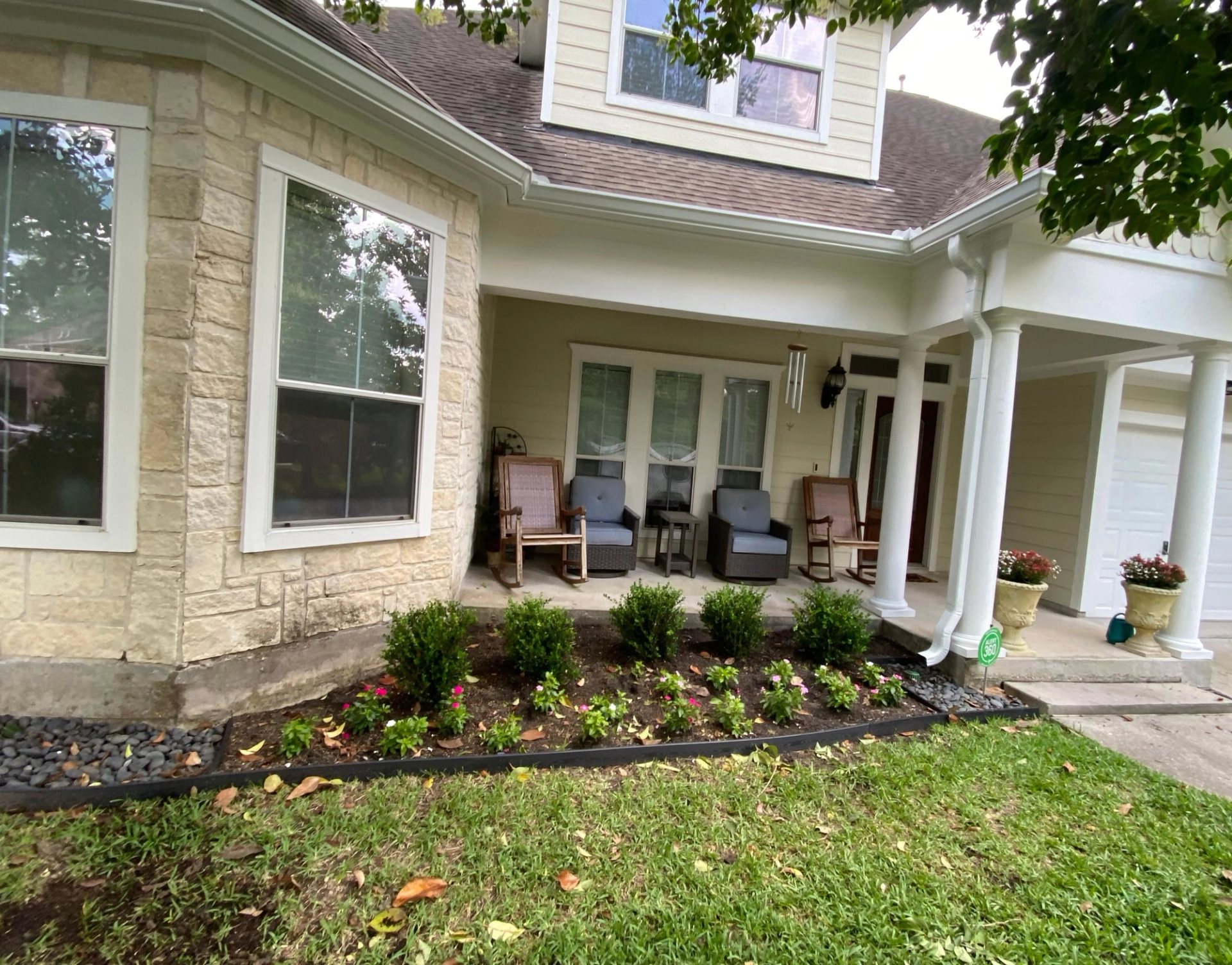 White 6-inch gutters along the stone bay window and covered front porch of a two-story Sterling Ridge home
